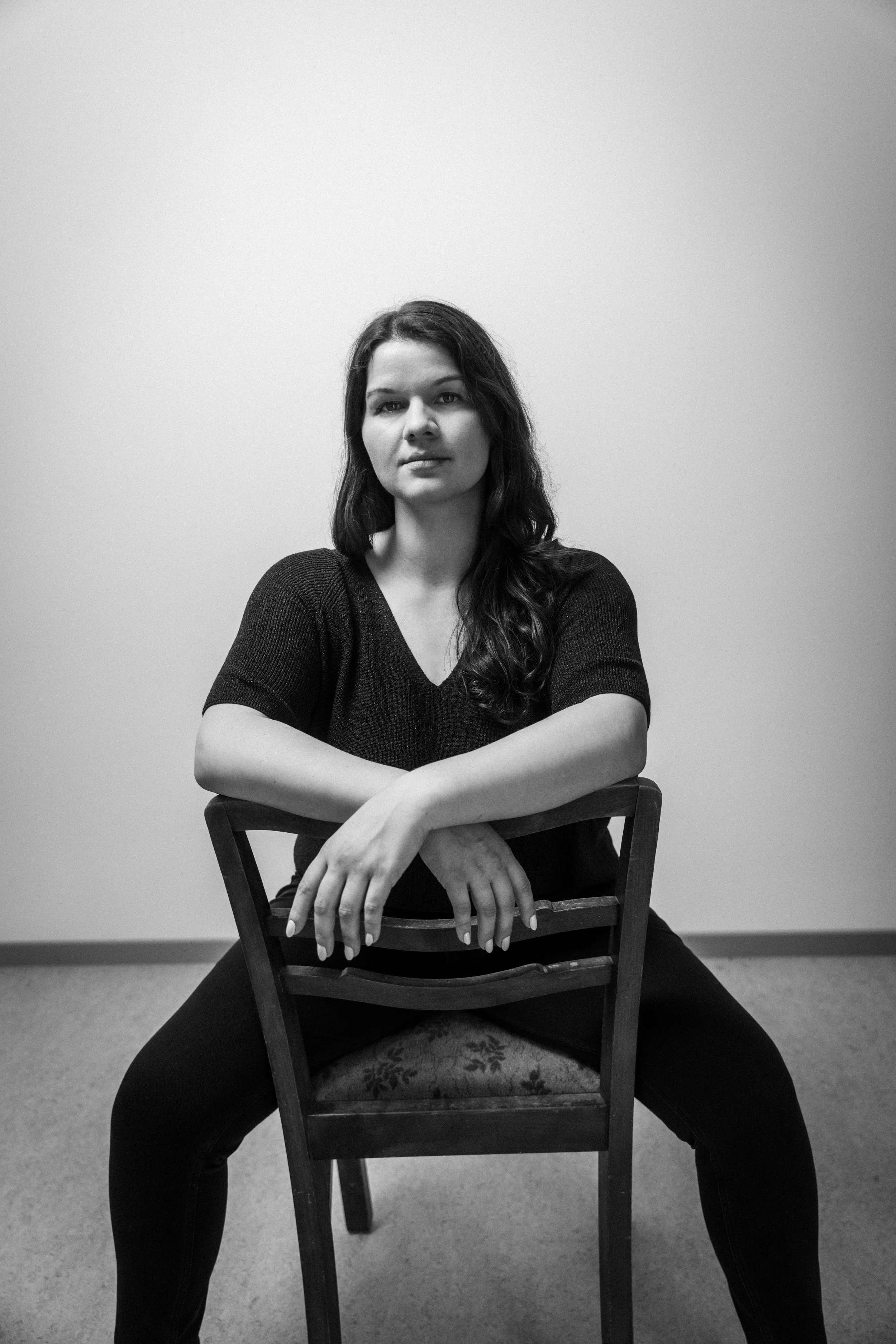 Schwarz-weiß Foto einer Frau, die auf einem Stuhl sitzt, mit den Beinen auseinander, Arme auf dem Stuhl.  Elina Beer spielt "Sabine" in  Das Wilde Weib – Das Musical · Birsteiner Festspiele 2027