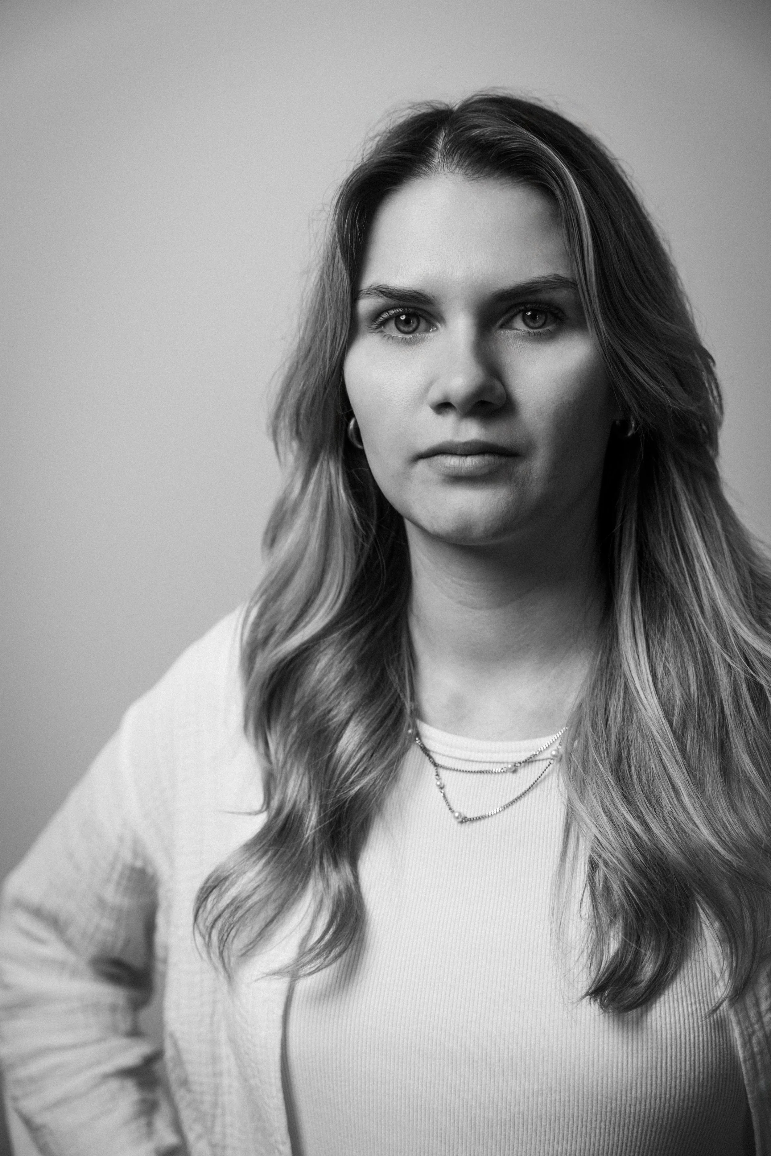 Schwarz-weiß Porträt einer jungen Frau mit langen, gewellten Haaren, die nach vorne schaut und eine neutrale Mimik zeigt. Jenna Sauer in  Das Wilde Weib – Das Musical · Birsteiner Festspiele 2027
