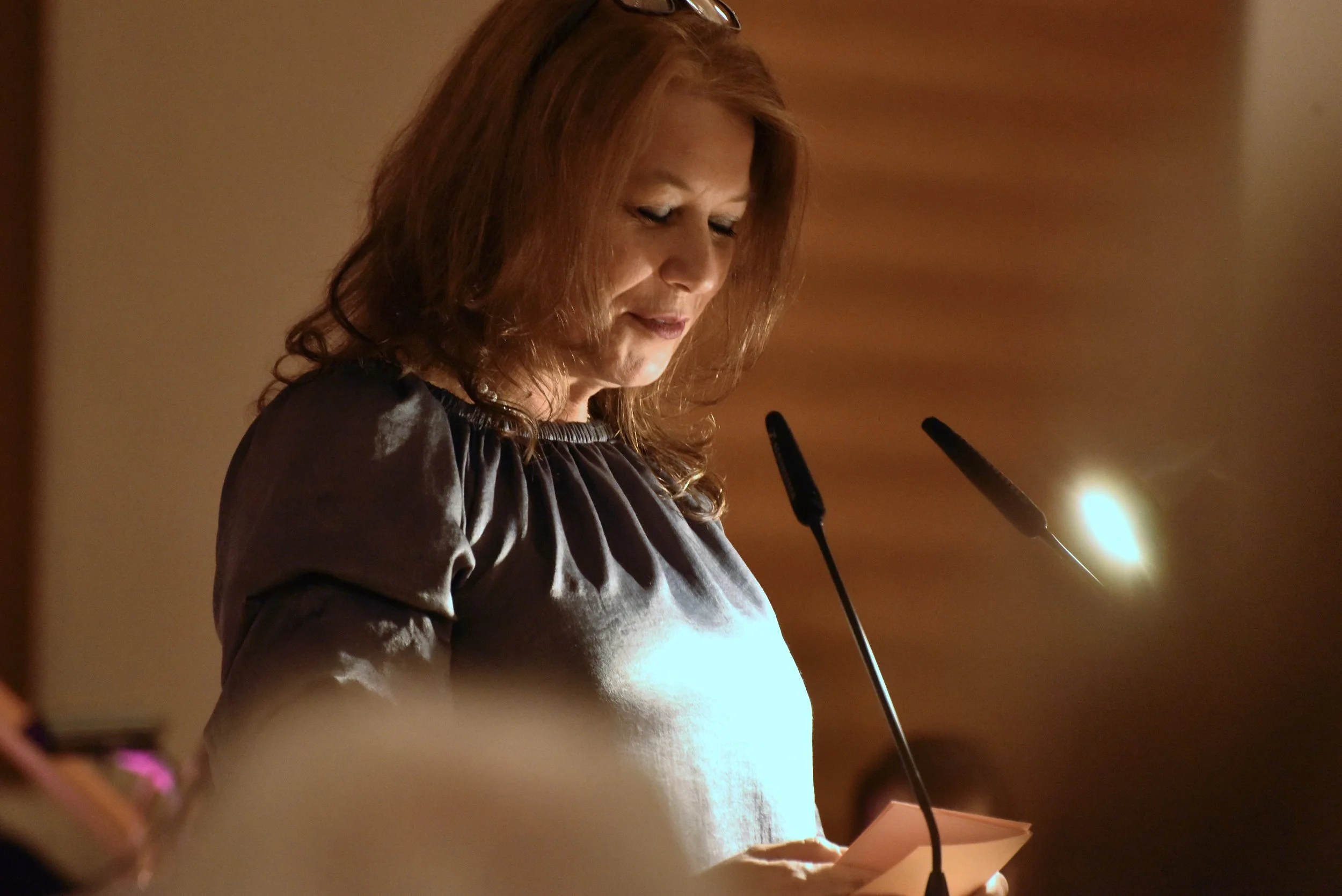 Angelika Roskoni am Rednerpult des Kulturpreises des Main-Kinzig-Kreis. Frau liest an einem Rednerpult während einer Veranstaltung, mit freundlicher Beleuchtung.