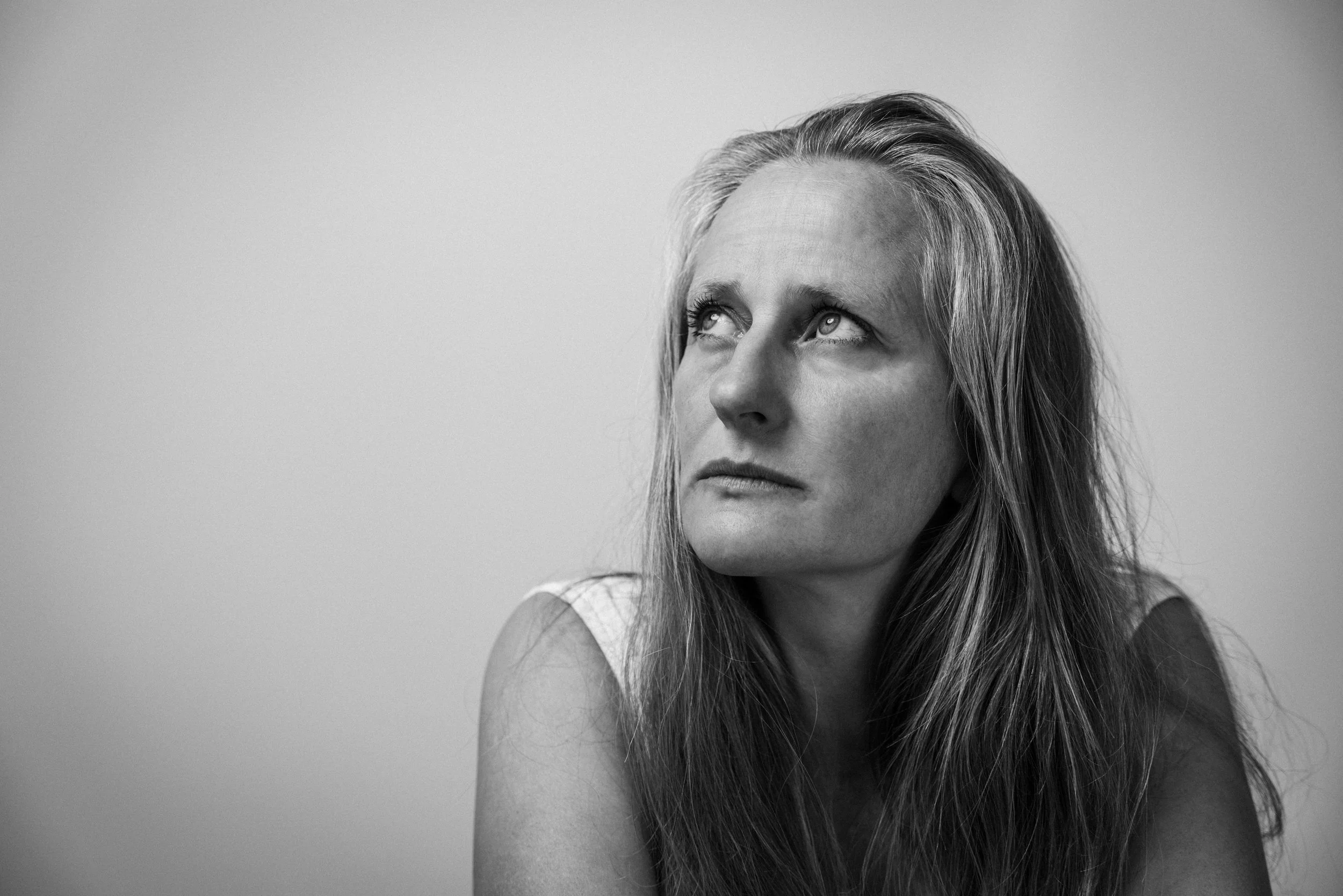Schwarz-weiß Portraitbild einer Frau mit langen Haaren, die nach oben schaut.