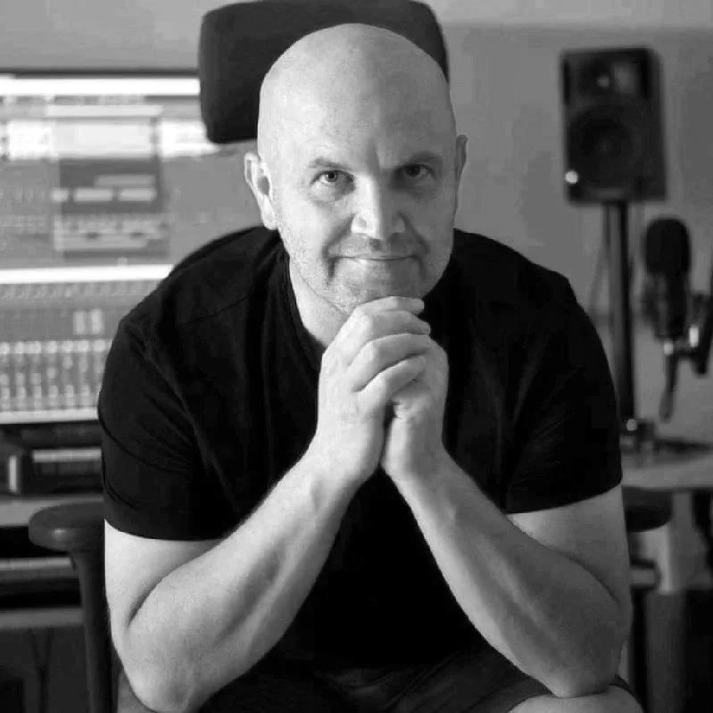 Jochen Flach, Komponist der Birsteiner Festspiele. Ein Mann sitzt in einem Tonstudio vor einem Computerbildschirm mit Musiksoftware, blickt direkt in die Kamera und hat die Hände vor seinem Gesicht verschränkt.