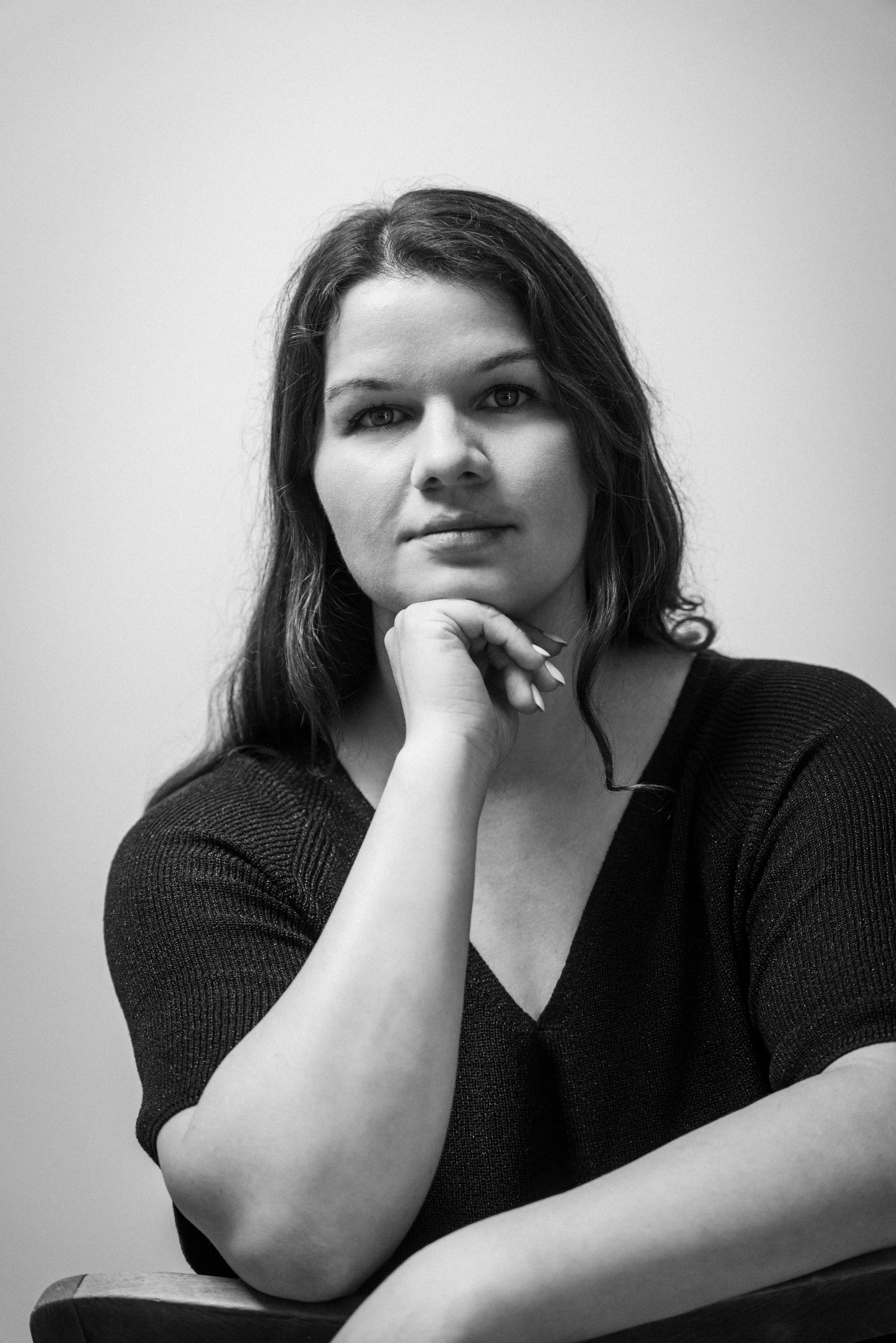 Schwarz-weiß-Fotografie einer Frau mit dunklem, langem Haar, die nachdenklich auf den Handkinn legt. Eline Beer in  Das Wilde Weib – Das Musical · Birsteiner Festspiele 2027