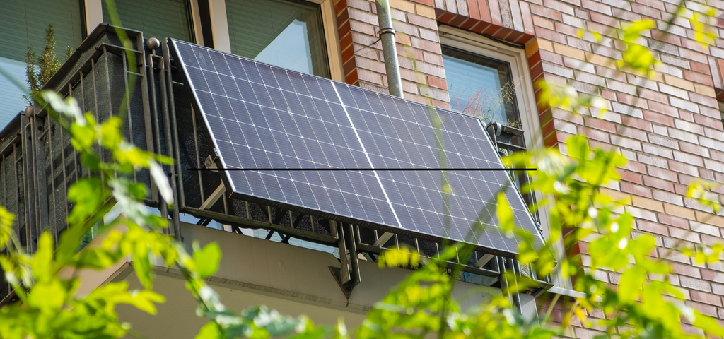 Solaranlage auf einem Balkon vor einem Fenster eines Hauses, umweltfreundliche Energiequelle.