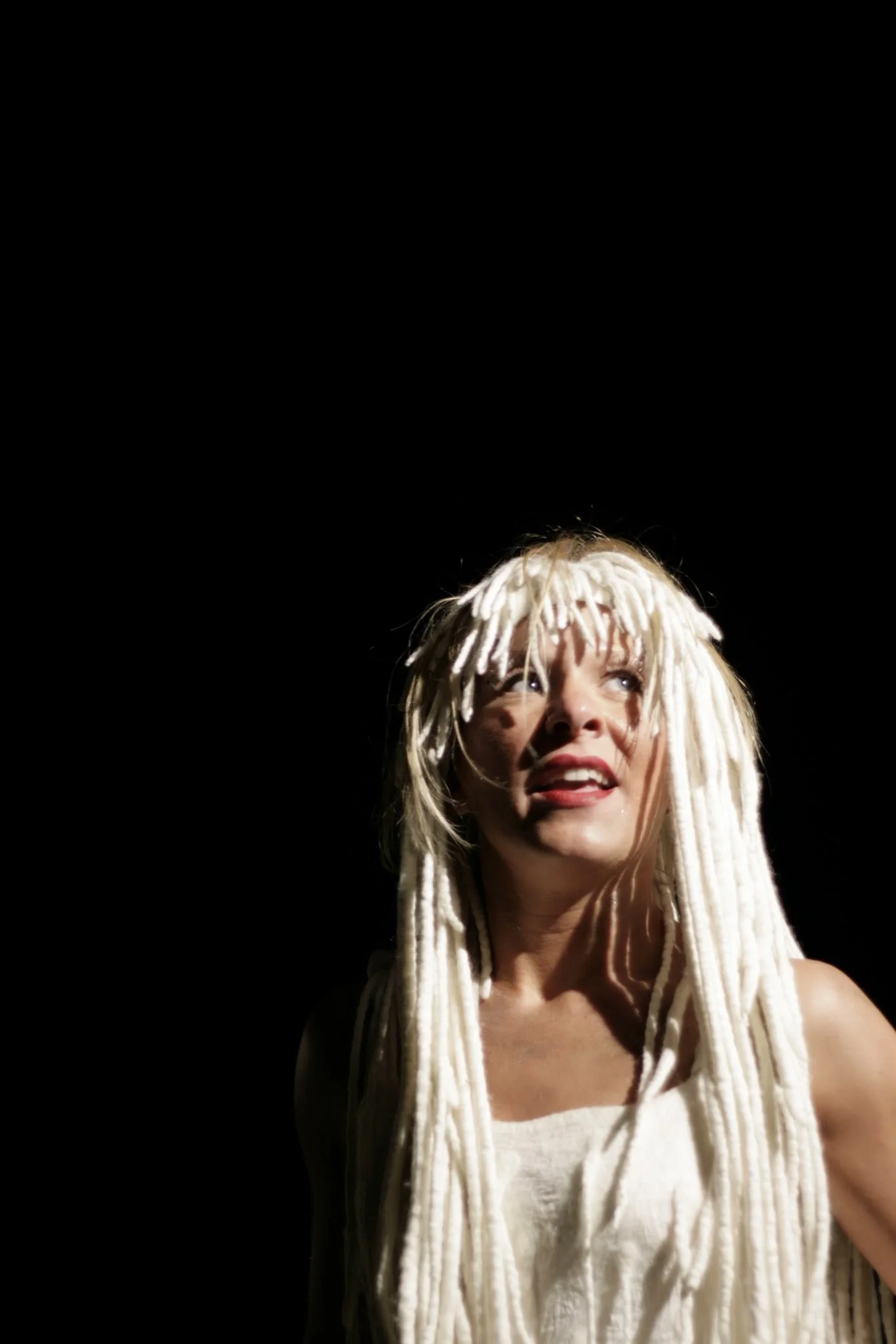 Frau mit weißen Dreadlocks looks nach oben, schwarzen Hintergrund.