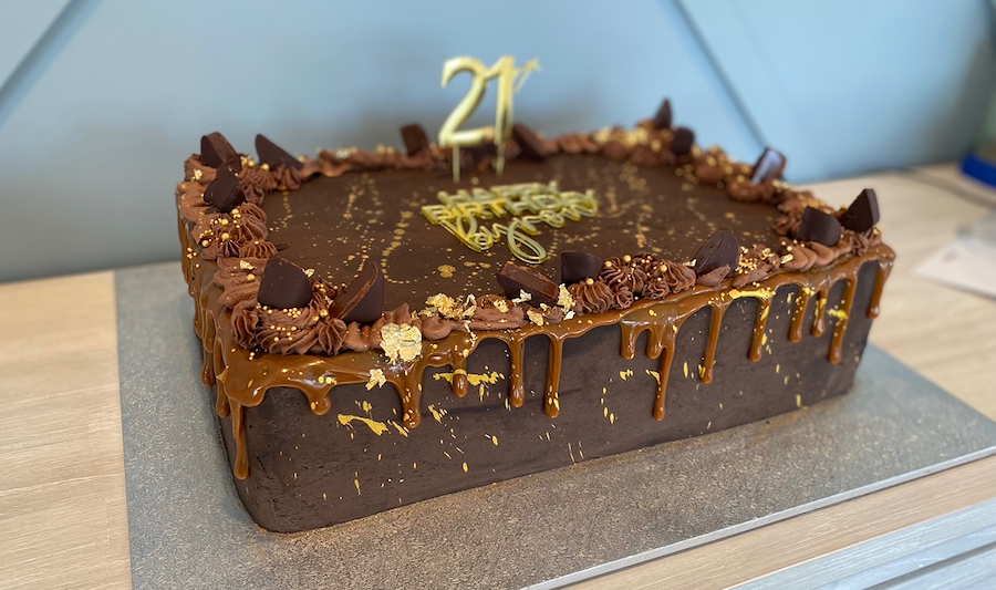 Chocolate birthday cake with gold decorations and a '21' topper.