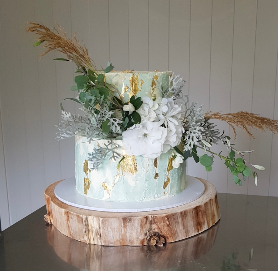Two tiered wedding cake, chocolate tier, and a carrot cake tier. Vanilla italian meringue buttercream thoughout in sage white and gold leaf.