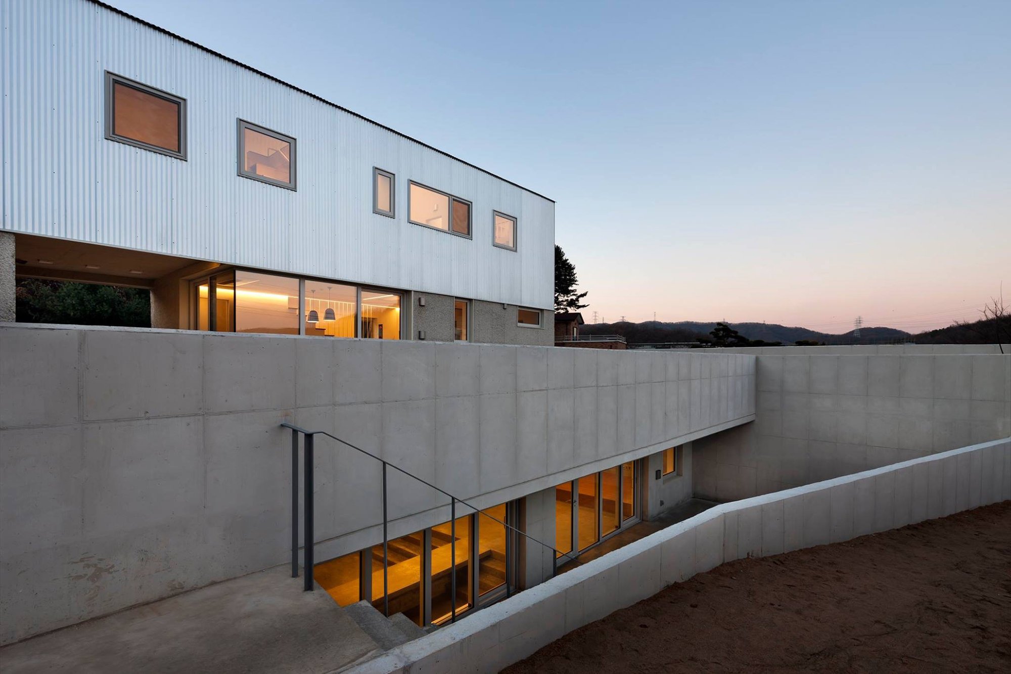 KimShin Design Studio Headquarters Expansive Wide View of Modern Concrete and Metal Architecture with Warm Interior Lights at Twilight in Yongin Korea