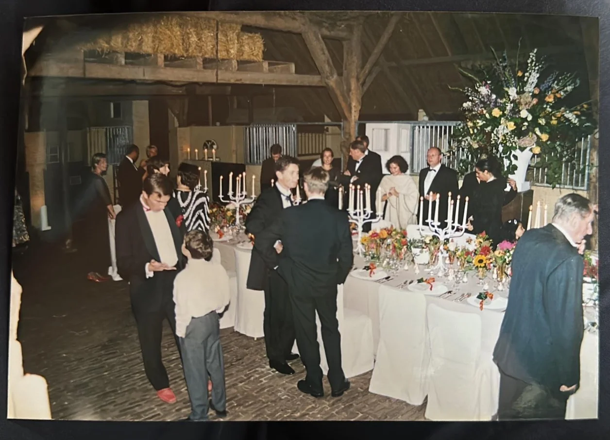 An old photograph of a candlelit dinner party in a countryside barn