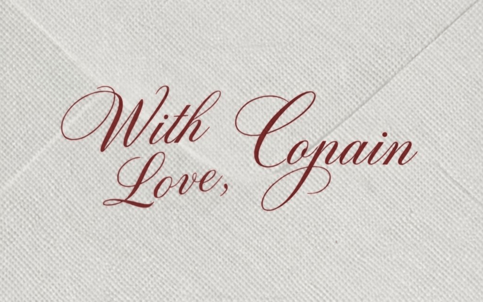 A cream envelope with the words With Love, Copain written across it in red script