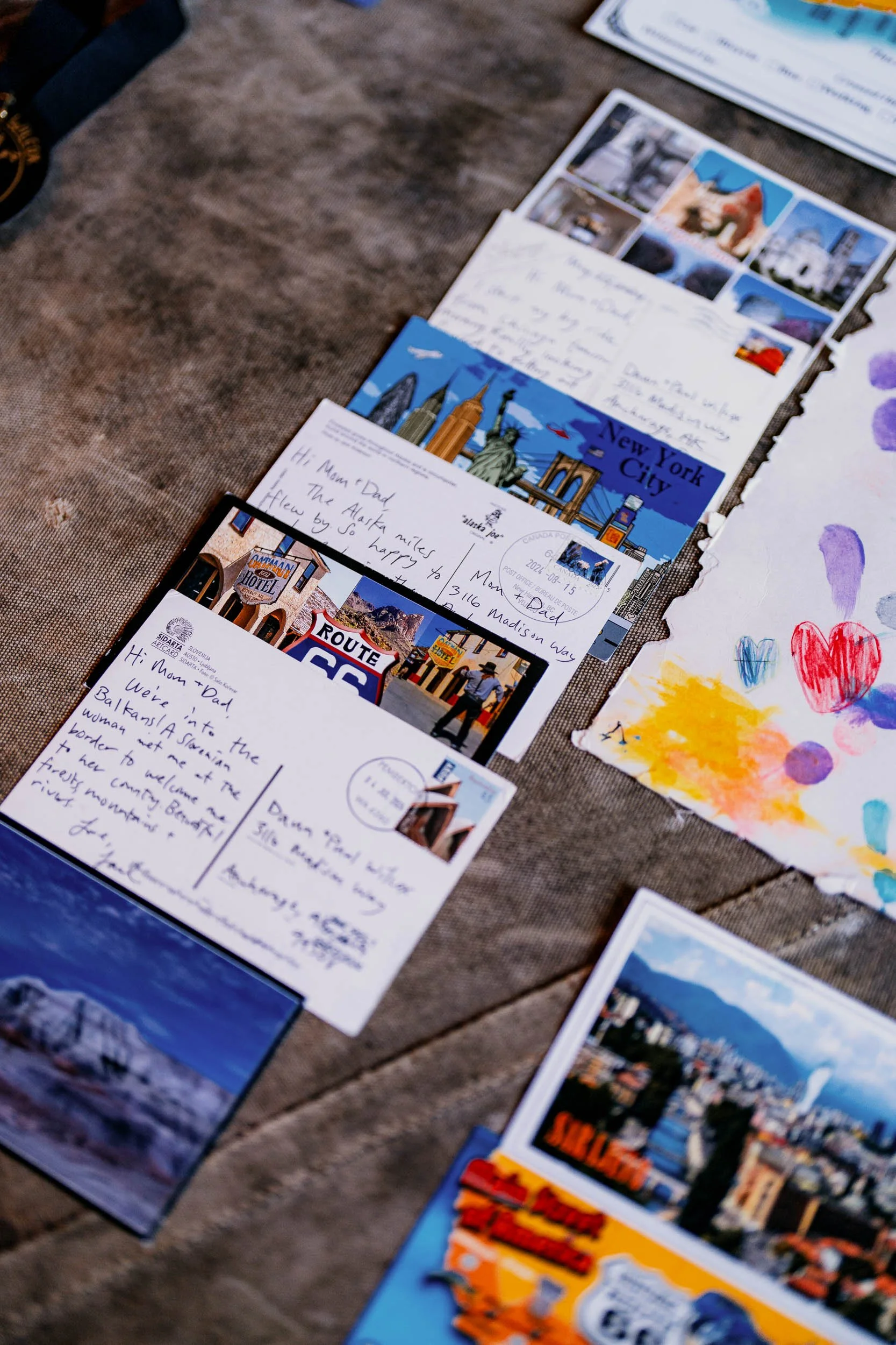 A row of postcards and handwritten letters laid out on a brown, weathered surface.