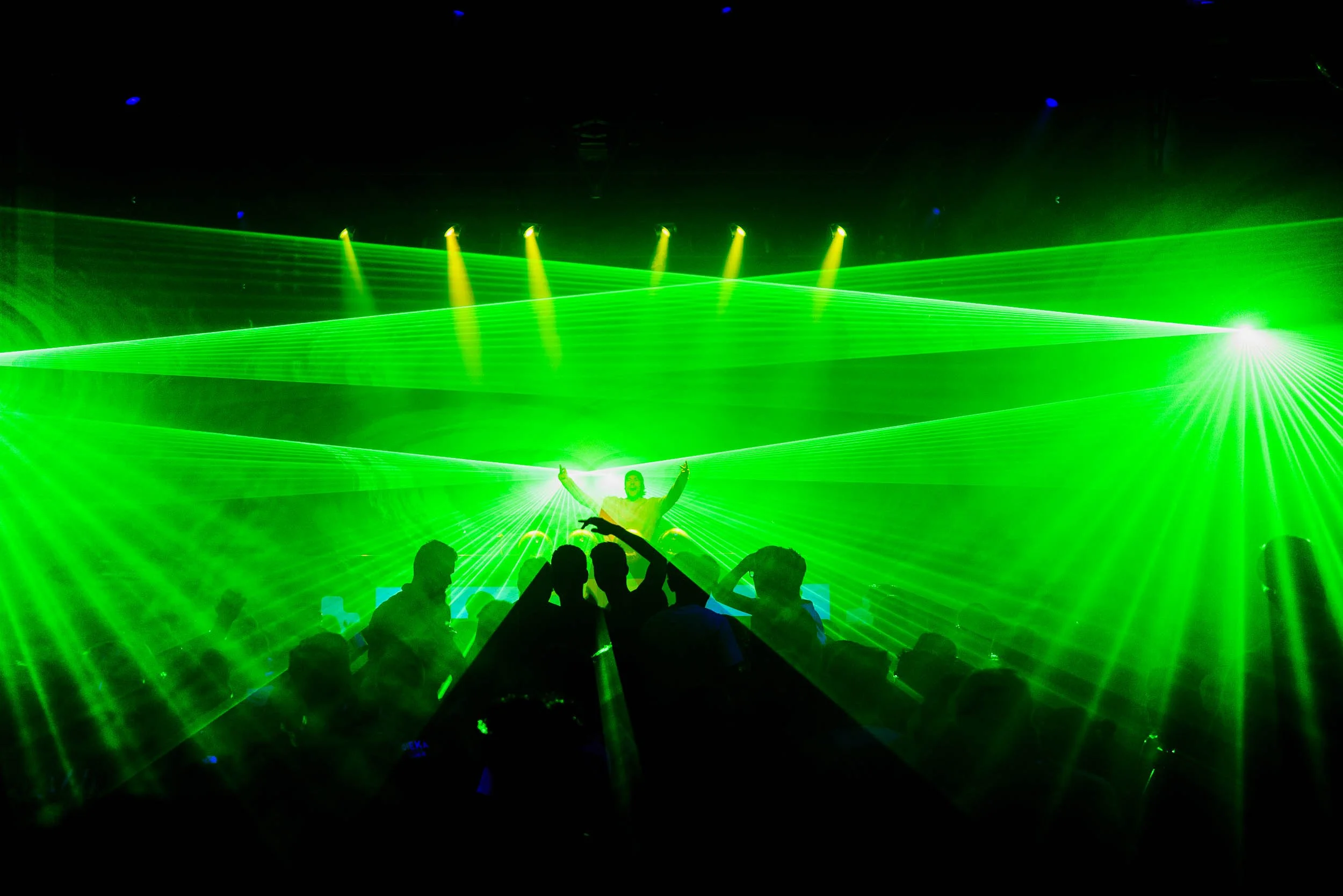 A concert scene with green laser lights and a DJ or performer on stage, with an audience dancing.  (Viktor Verhulst)
