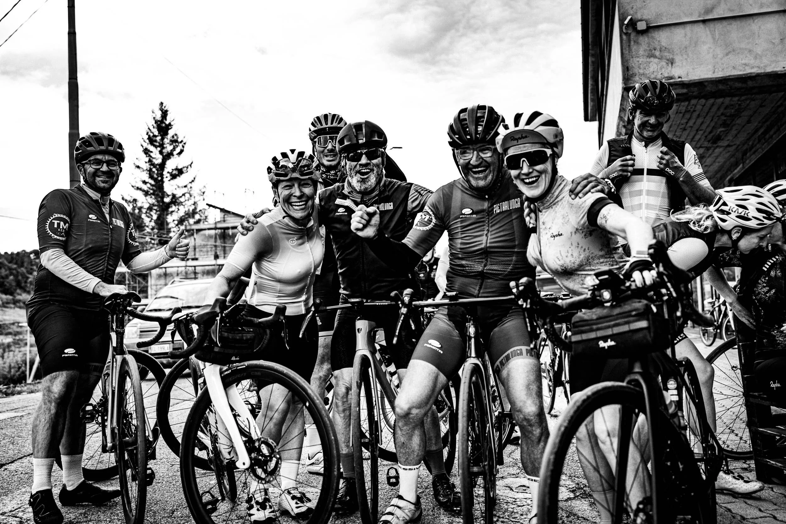 A group of cyclists posing with their bikes outdoors, smiling and celebrating.