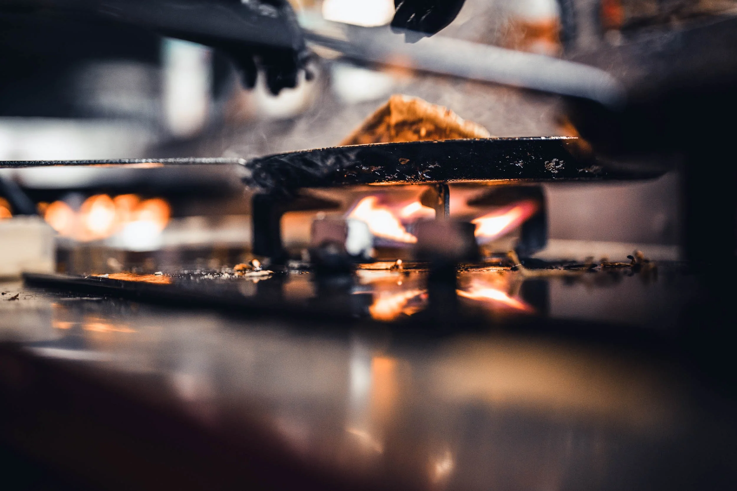 Close-up of a burning stove with flames, with a piece of food cooking on the burner.