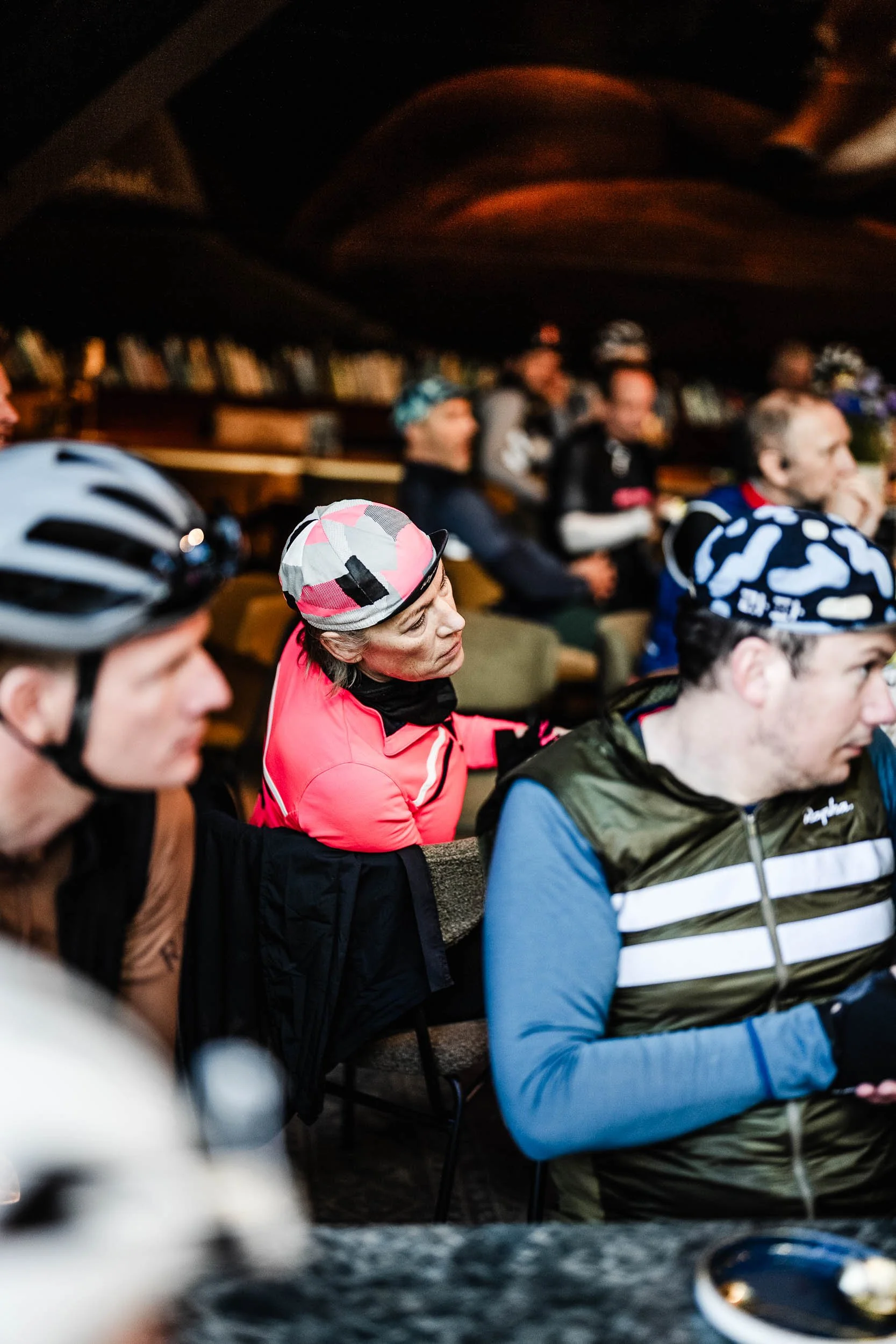 A group of people wearing cycling helmets and casual clothing seated indoors, possibly attending a meeting or presentation.