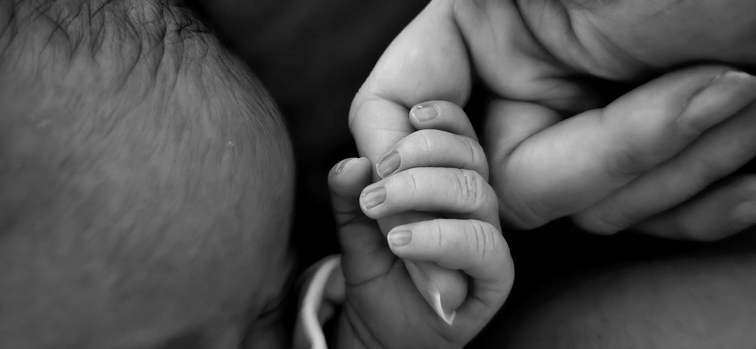 baby holding hand of mother