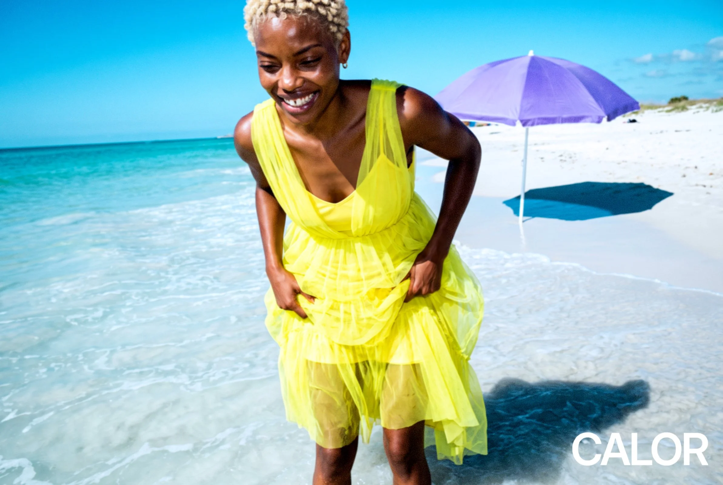 mixed model 25 years old smiling happy yellow dress in turquoise water white beach sunshine