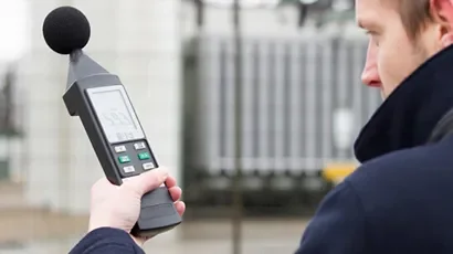 Person holding a sound level meter outdoors