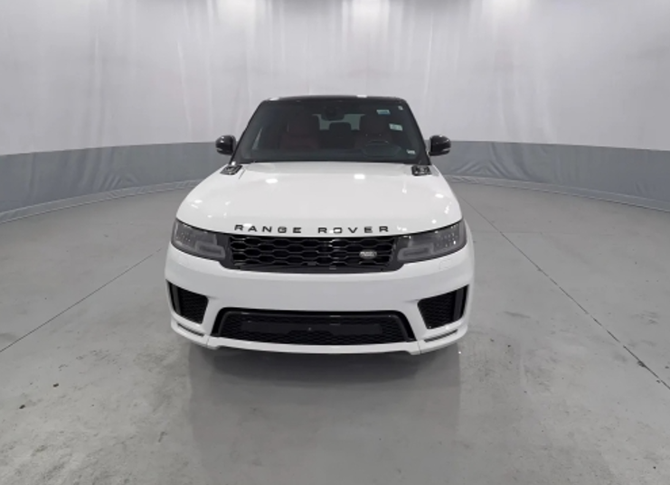 Front view of a white Range Rover SUV in a circular, indoor studio with plain walls.