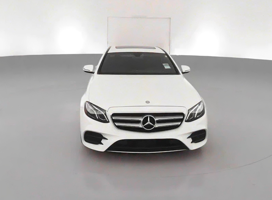White Mercedes-Benz sedan in a showroom with a plain white background.