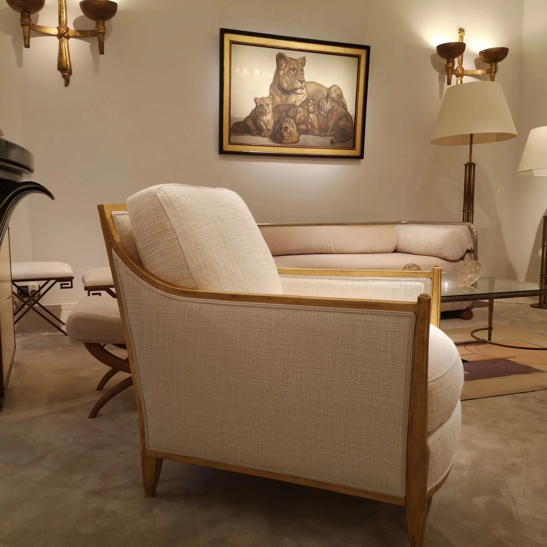 Salon avec un tableau représentant une lionne et ses lionceaux, meubles en bois, lampes avec appliques murales en laiton.