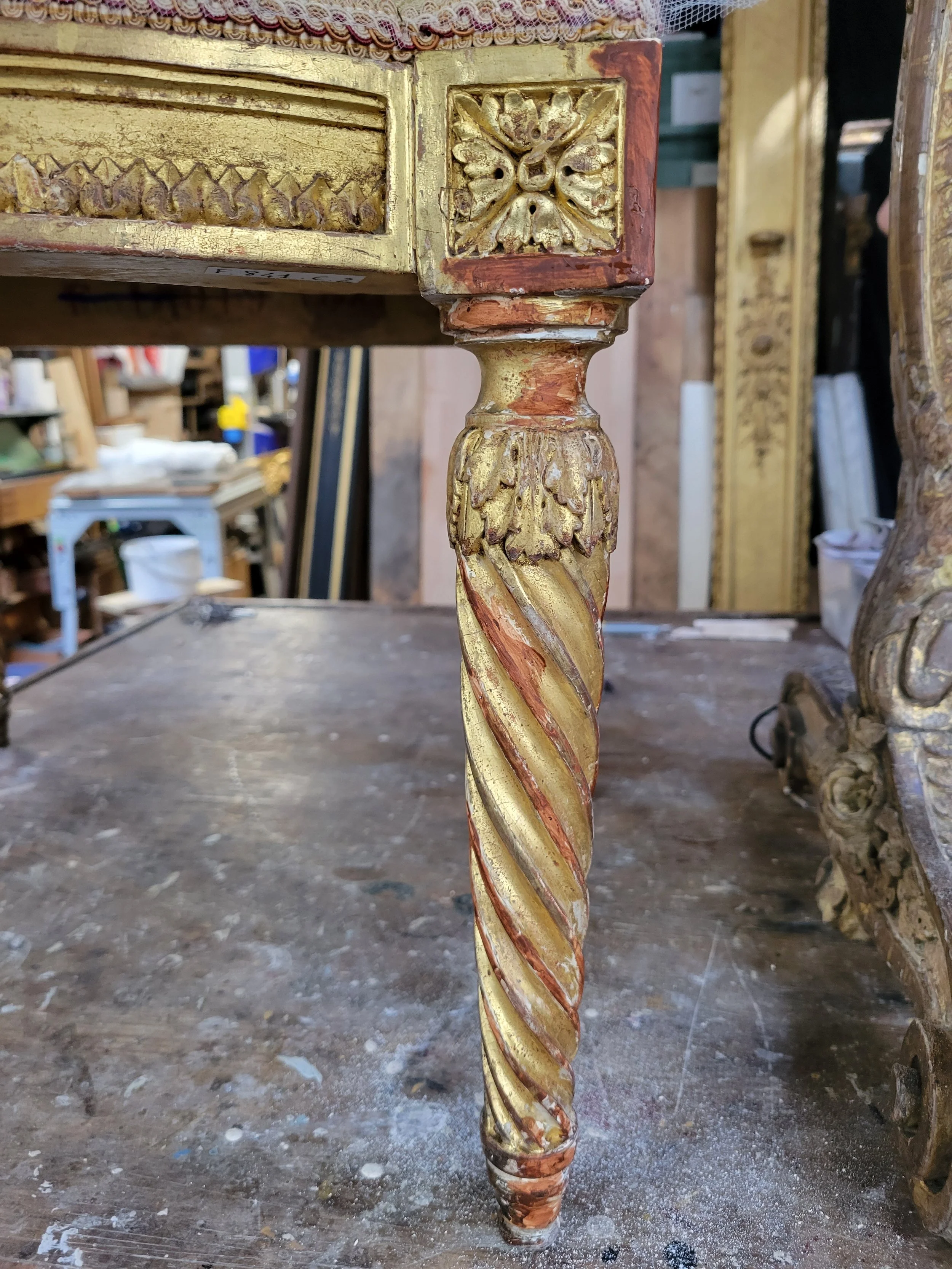 Détail d'une patère ancienne en bois sculpté orné de dorure, avec un décor floral et tourné en spirale.