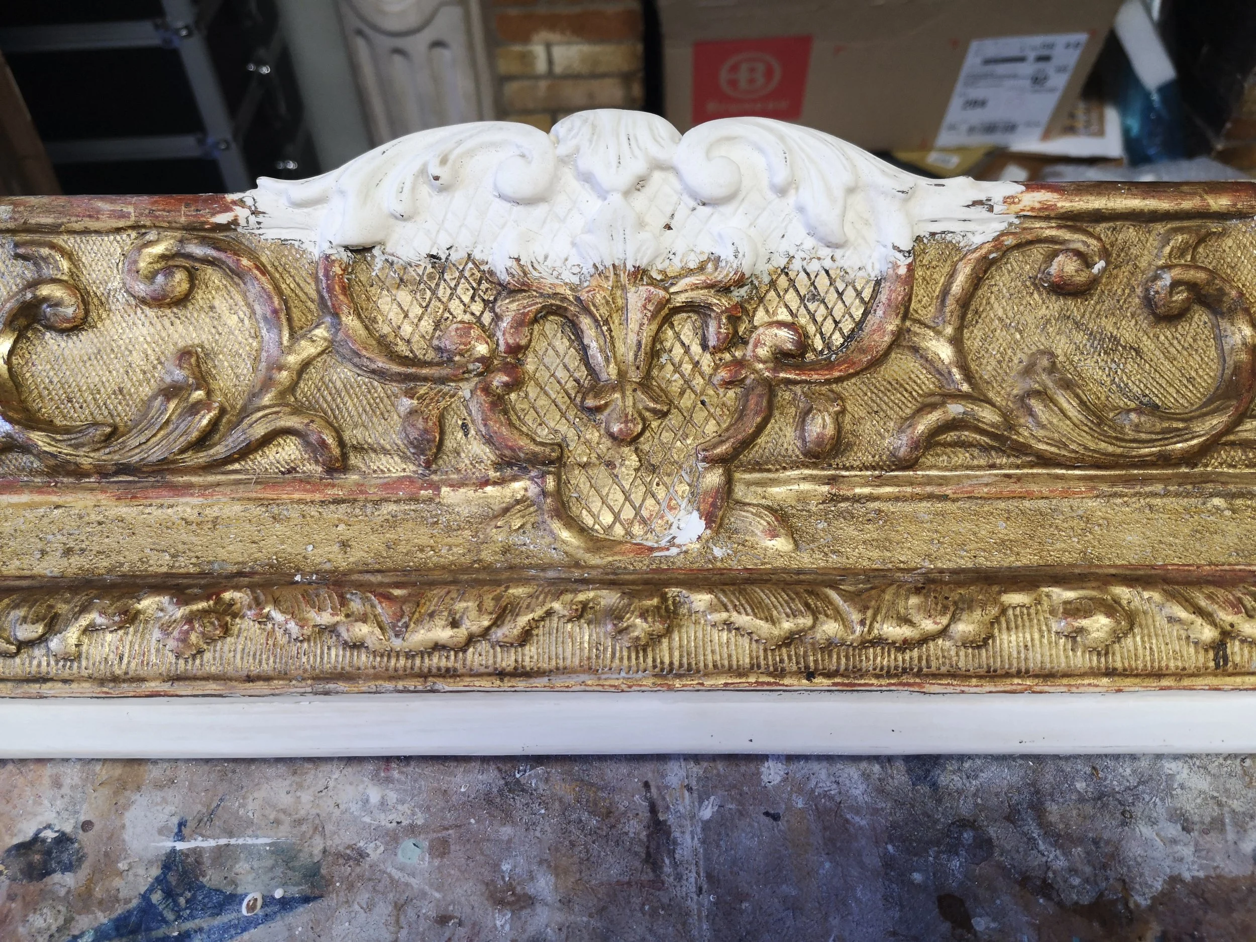 Dettaglio di un mobile antico dipinto in oro con decorazioni intagliate e una parte in rilievo bianca decorativa