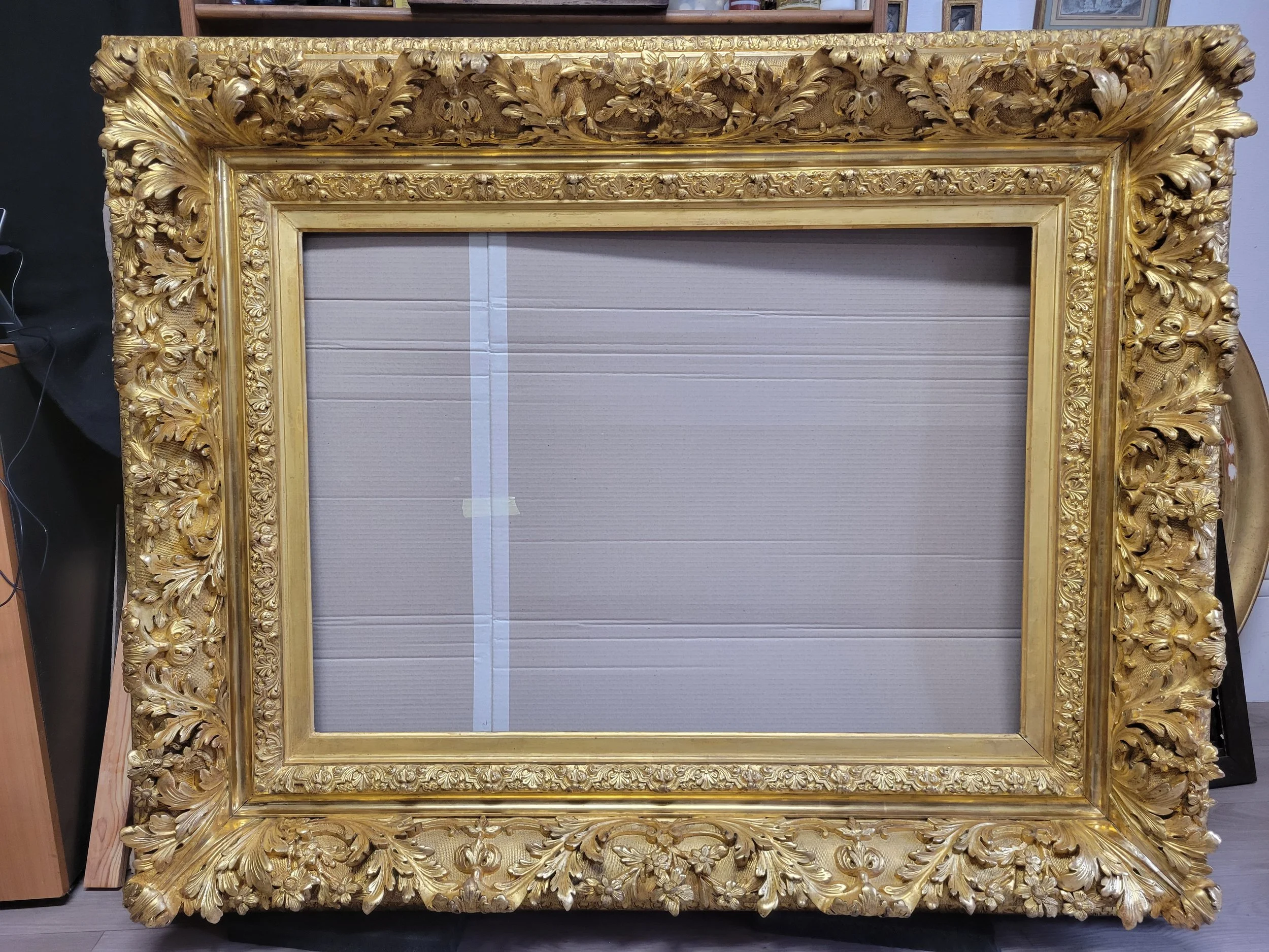 Cadre ancien et orné de motifs floraux et de feuilles sculptées en bois doré, probablement destiné à encadrer une peinture ou une œuvre d'art.