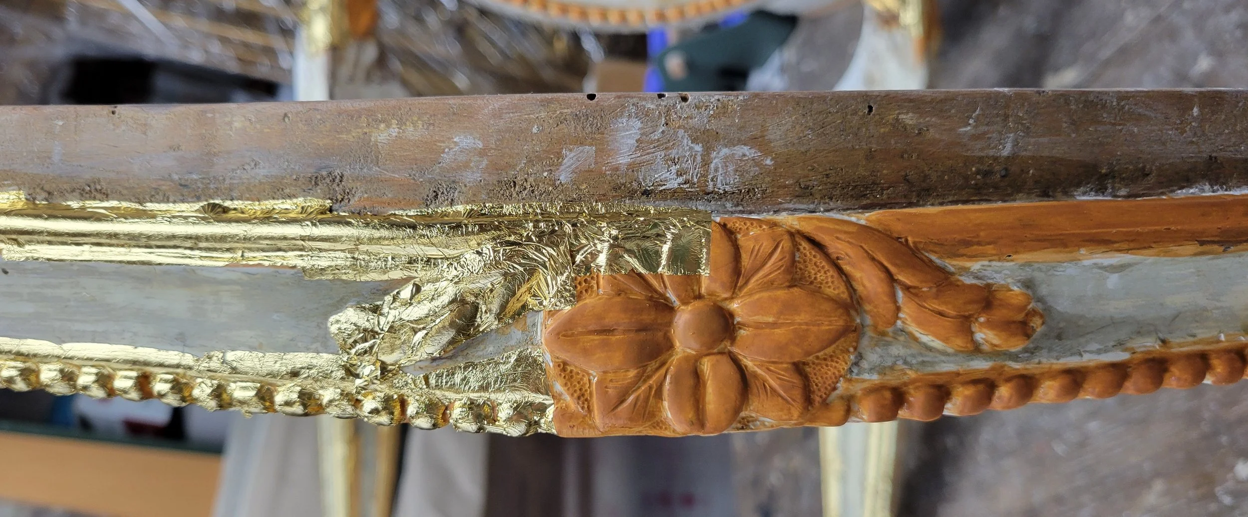 Détails d'une décoration en bois avec des éléments en feuilles d'or et un motif florale sculpté.
