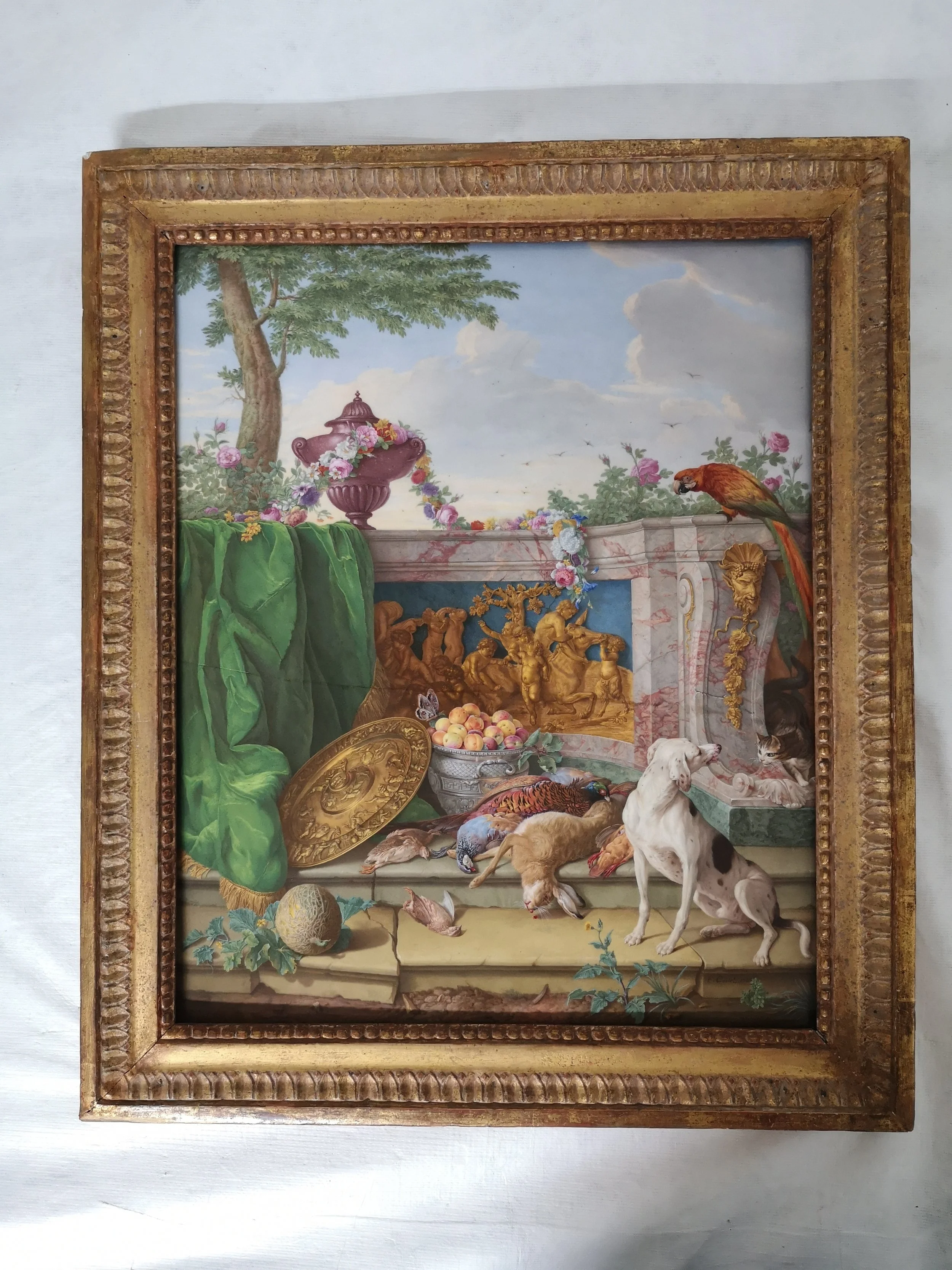 Tableau de nature morte avec animaux, fruits, vaisselle en or, draperies vertes, et objets divers dans un décor de pierre et de ciel. Un perroquet, chiens, pigeons, et poules sont visibles.