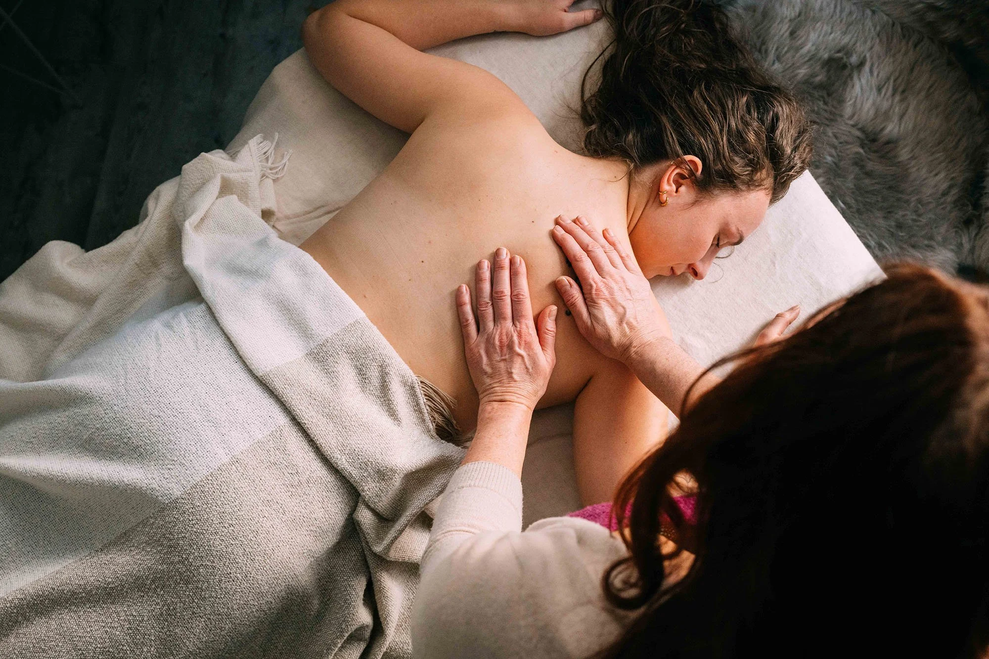 Asiakas makaa vatsallaan ja vastaanottaa Rosen-hoitoa Kehon aalloilla Rosen-terapeutin koskettaessa kahdella kädellä asiakkaan selkää.