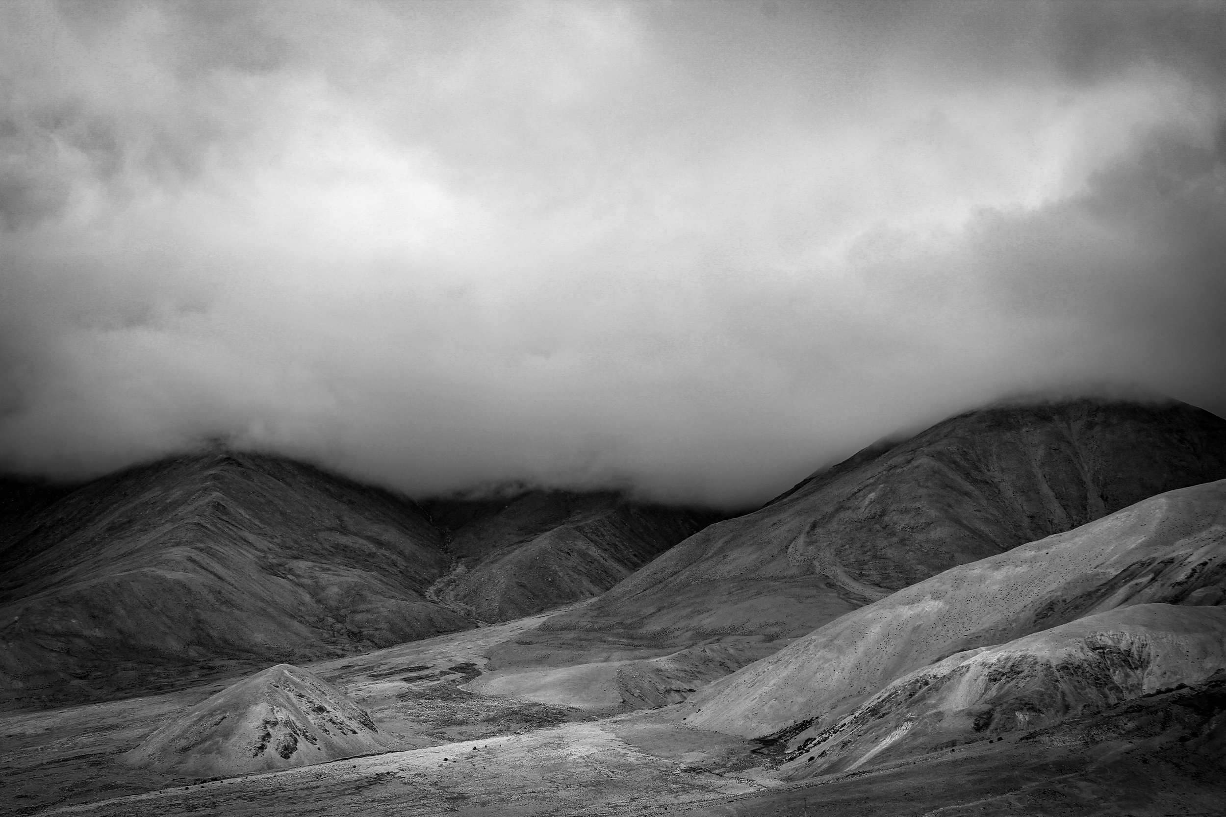 Black and white photograph of a mountainous landscape with cloud-covered peaks.