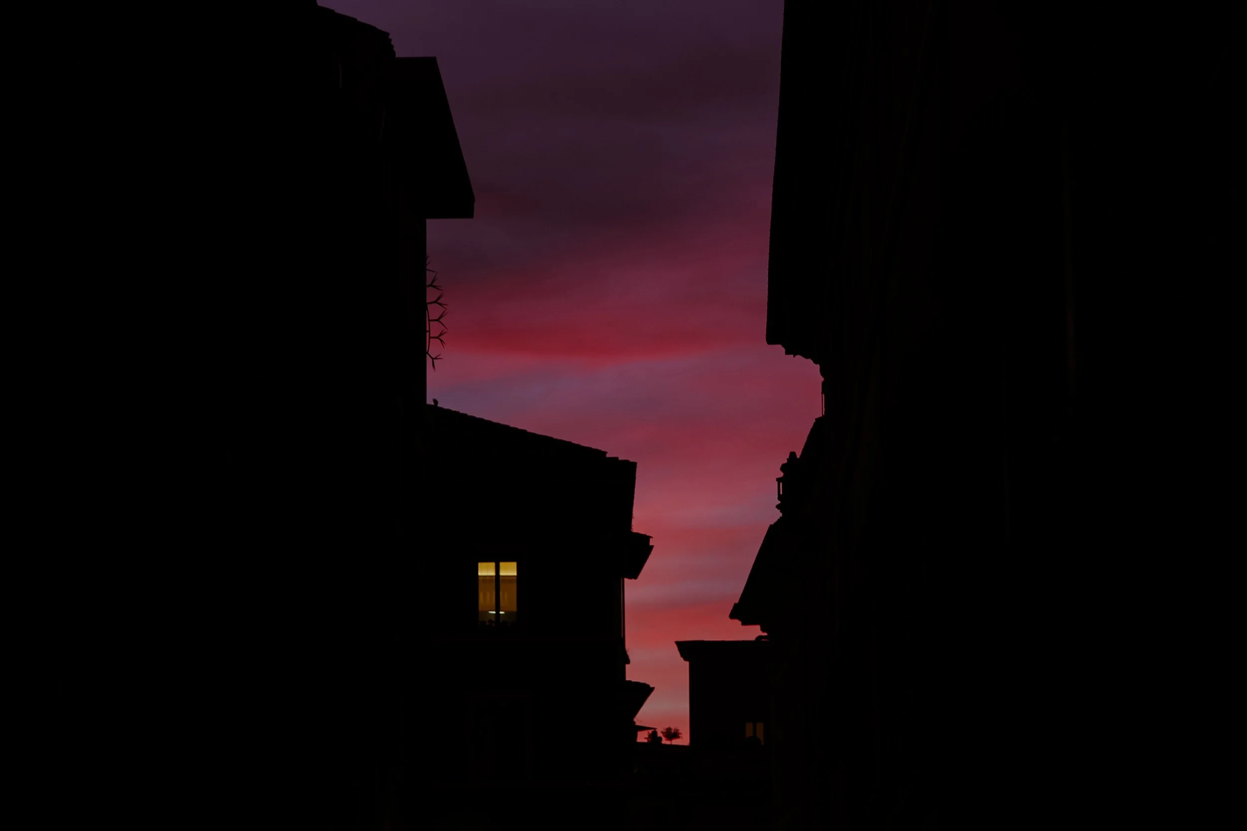 Silhouetted buildings at sunset with pink and purple sky.