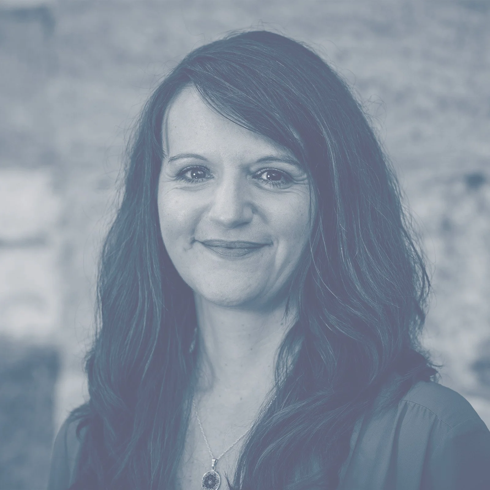 Porträt einer Frau mit langen dunklen Haaren vor einem unscharfen Hintergrund.