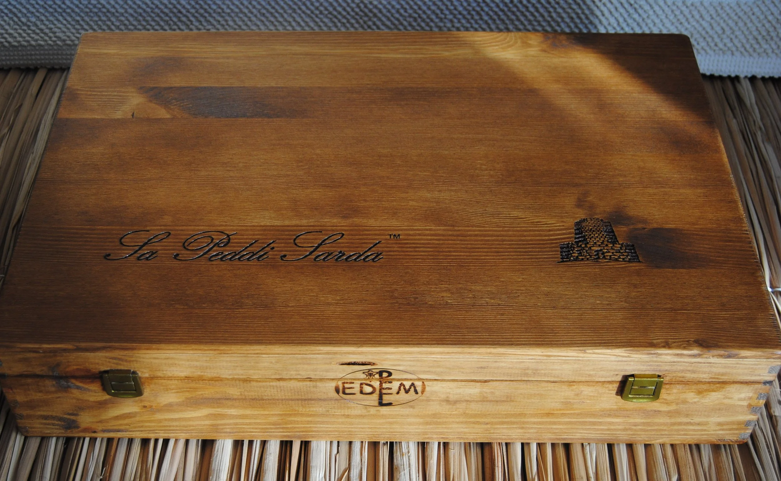 Exclusive natural wooden chest with hot-branded sa peddi sarda™ logo and brass clasps, designed by Tuveri Edmondo for EDEM/PEL SRL.