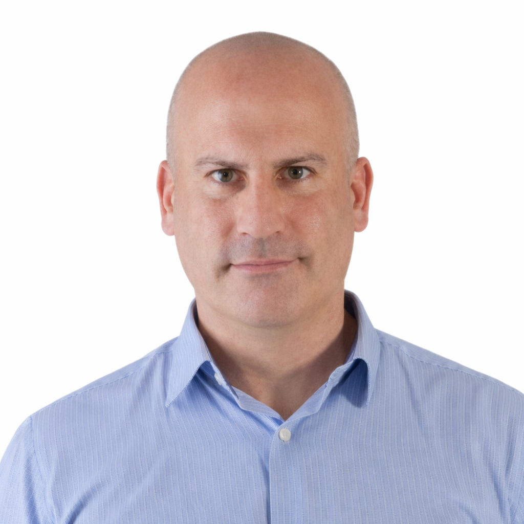 Portrait of a bald man in a light blue button-up shirt against a plain background.