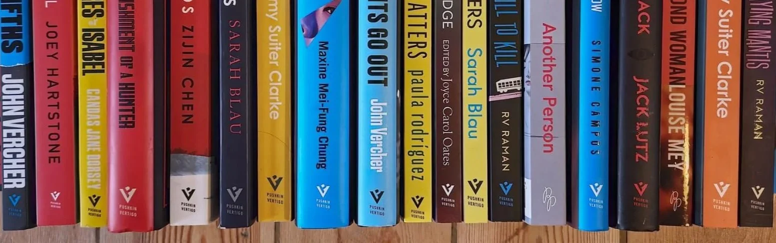 A row of colorful books on a shelf with their spines facing outward, displaying titles and authors.