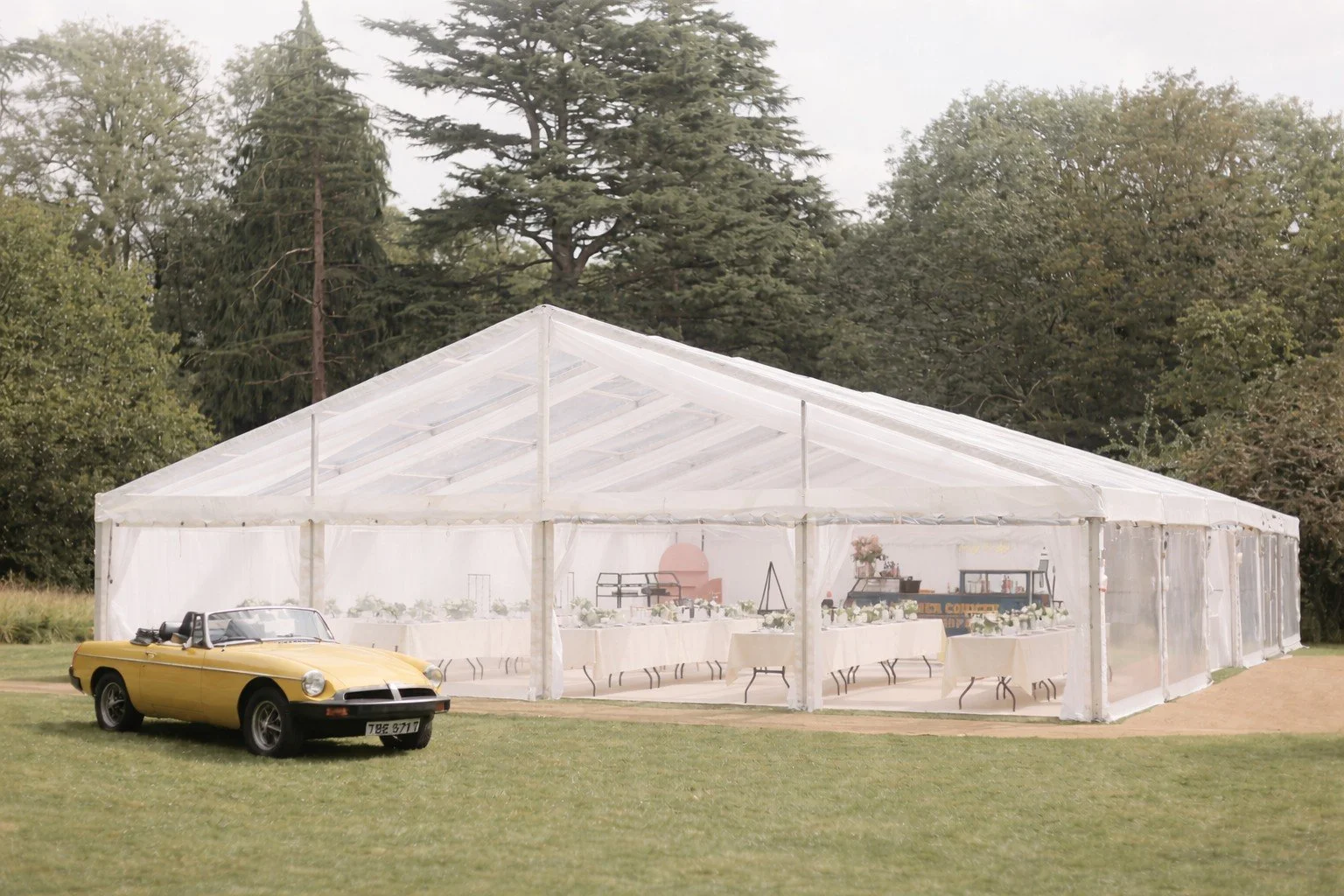 Elegant outdoor marquee event with refined tablescapes and vintage car, designed by Rêve Atelier
