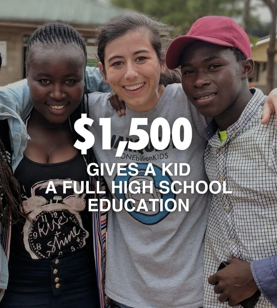 Three smiling children, one girl and two boys, stand closely together outdoors. The girl in the middle wears a gray T-shirt and has her arms around the boys. The boy on the right wears a red cap and a checkered shirt. The girl on the left has braids and is wearing a black shirt, partly covered by a light jacket. Text overlay reads '$1,500 gives a kid a full high school education.'