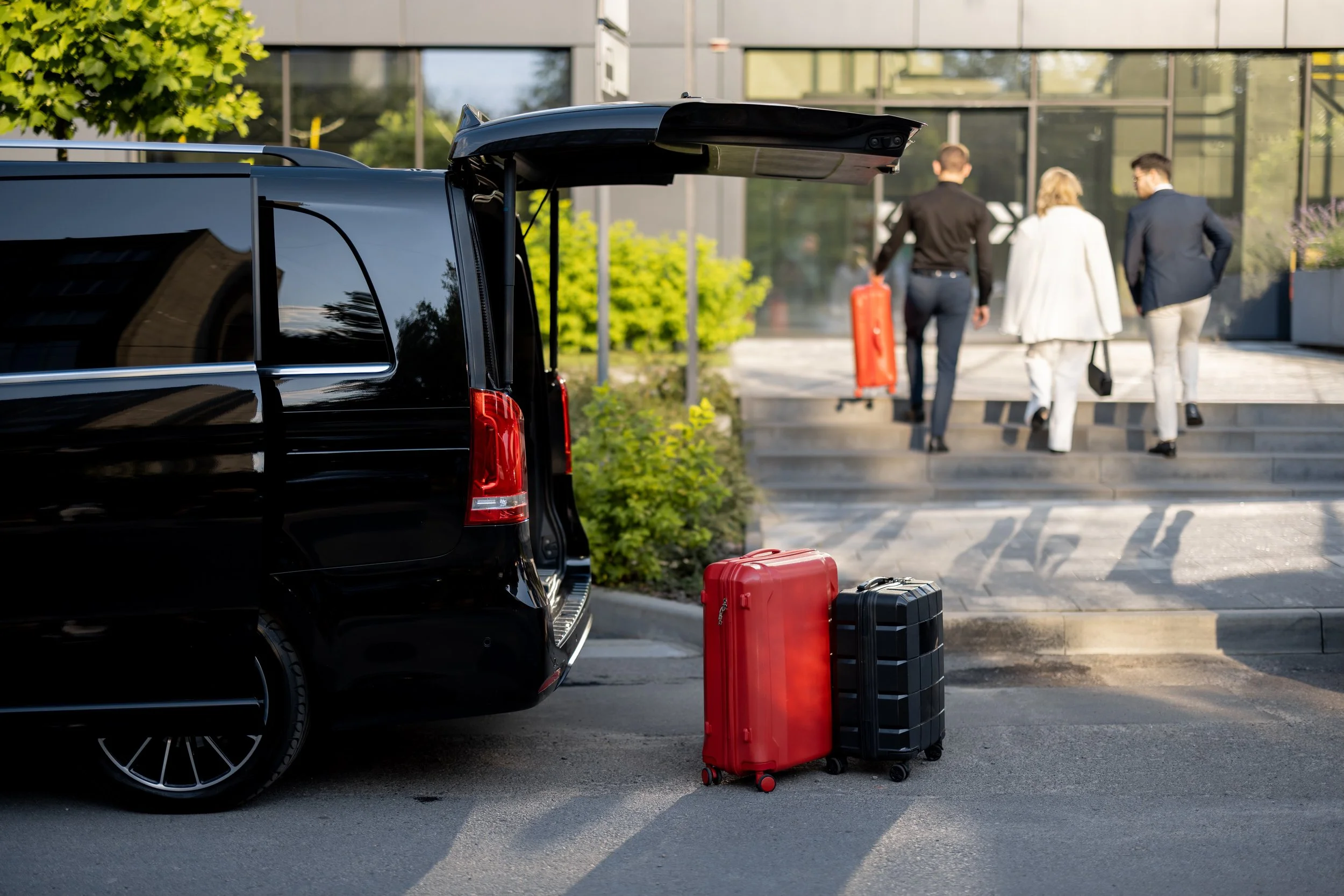 driver helping business couple carry their suitcases to the car from hotel