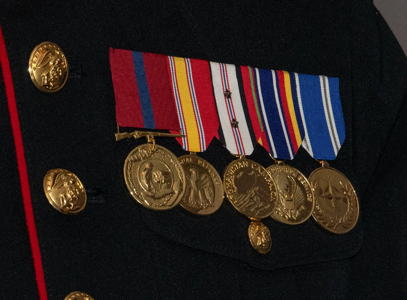 Close-up of a United States Marine Corps uniform showing medals, ribbons, and gold buttons.