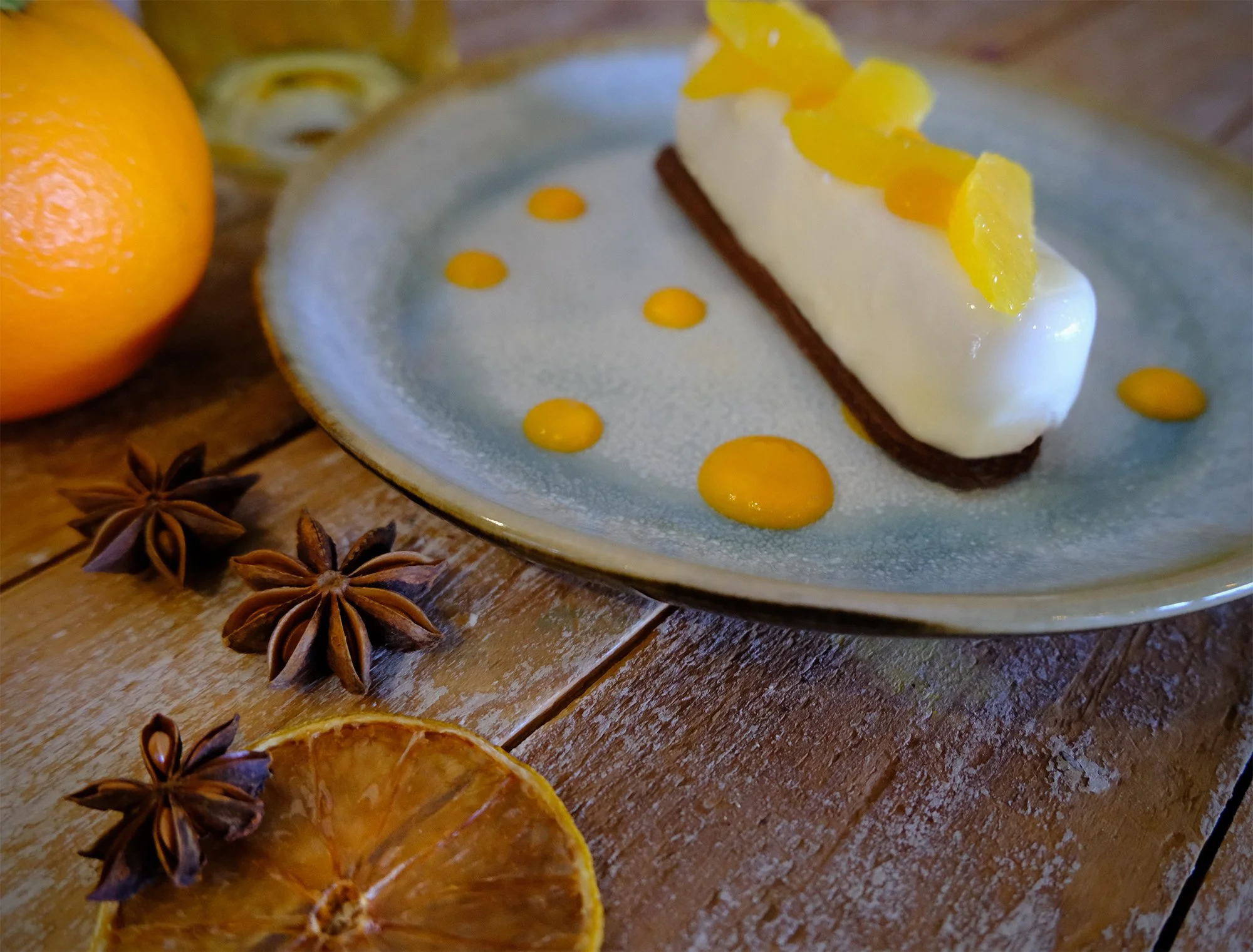 Entremet orange sur une assiette, entouré d'oranges séchées et d'épices star anisée, menu février 2026