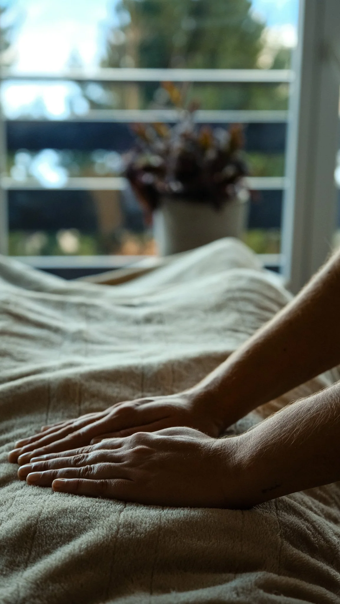 Une personne allongée sur une table de massage, sous une couverture douce, les mains de la thérapeute poséees sur le ventre.