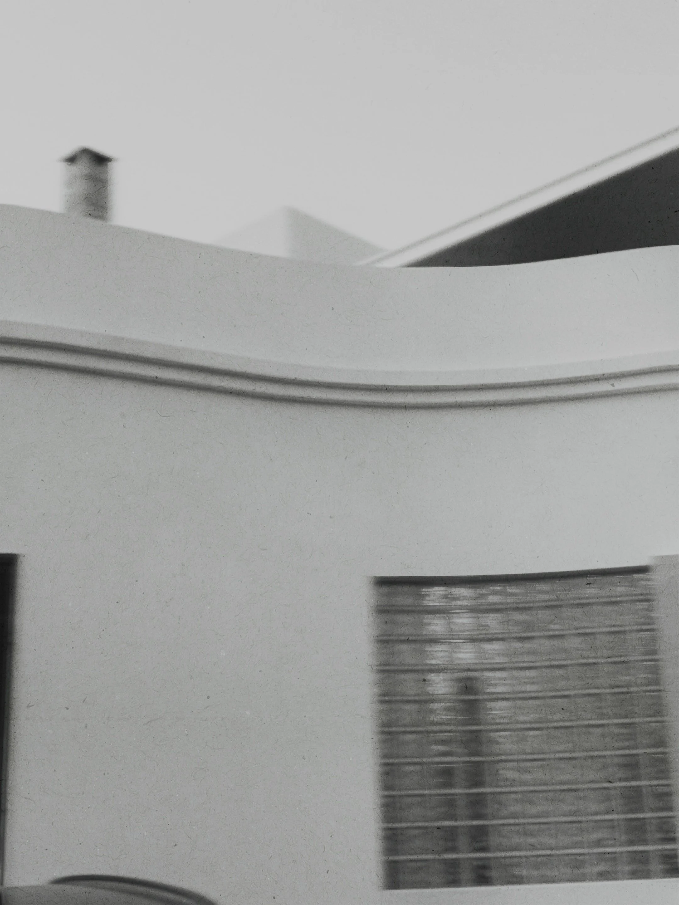 Close-up of a modern building in Lanzarote with curved and straight architectural features, including a glass brick window.