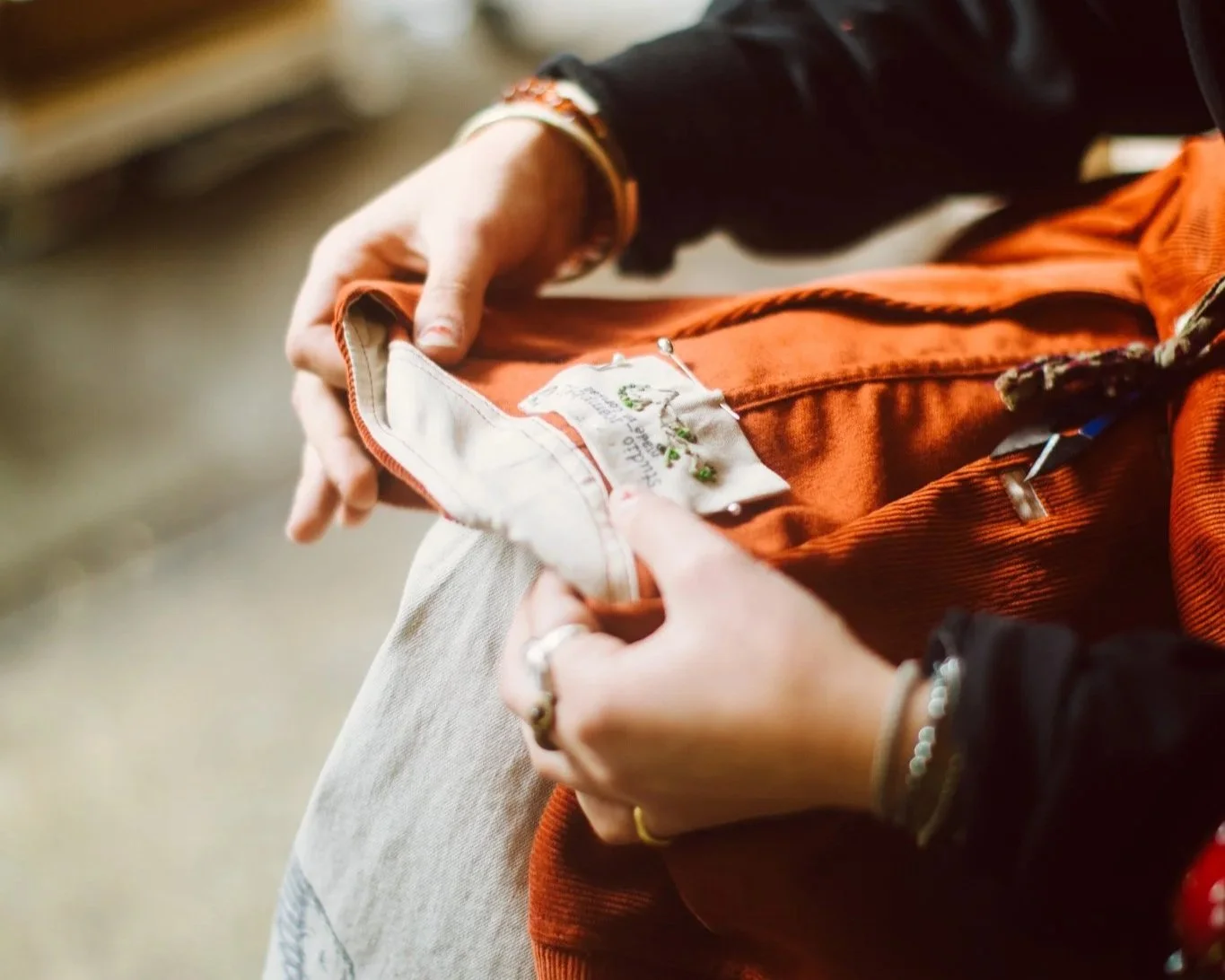 A person sewing or repairing a fabric item with a hand needle in a cozy indoor setting.