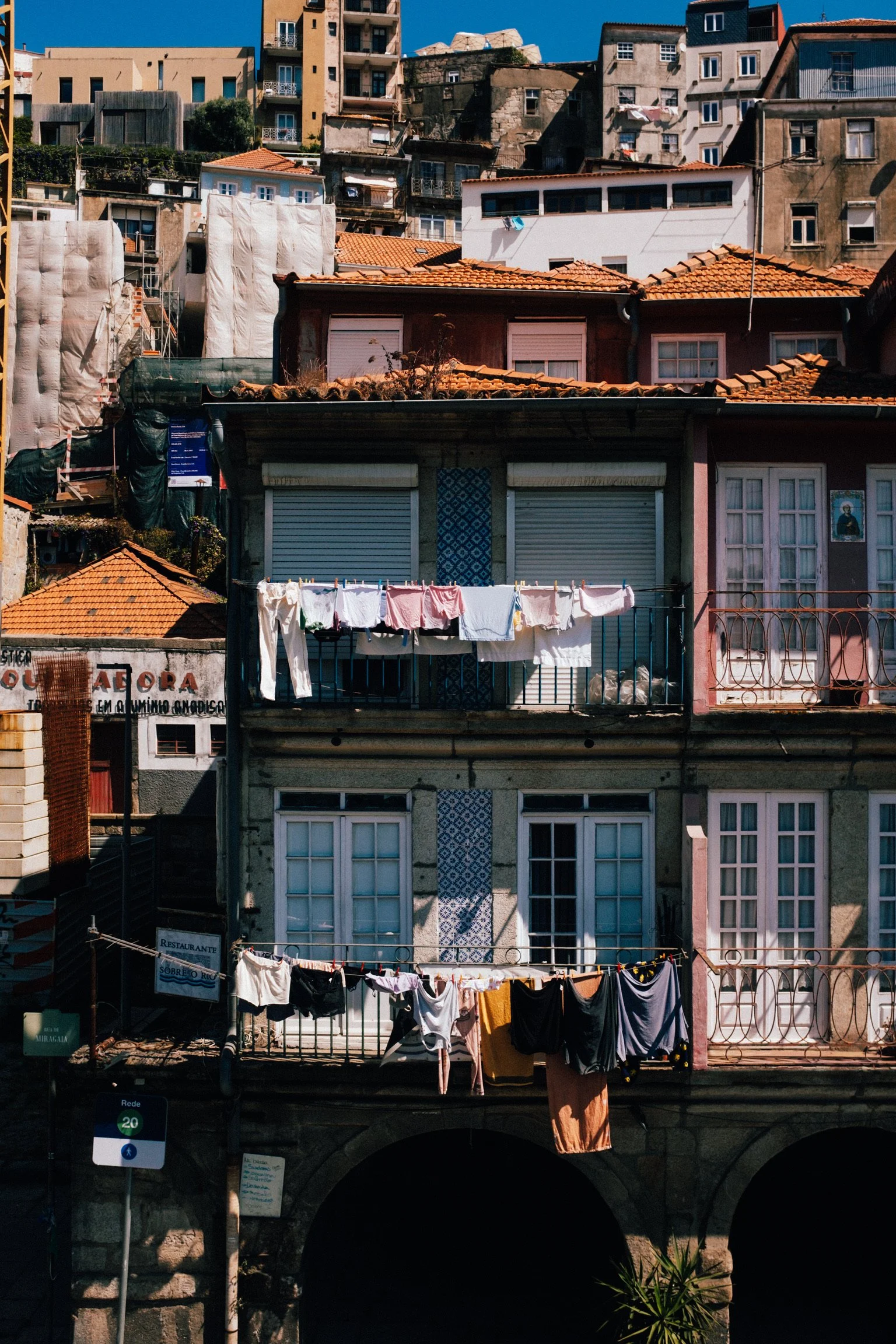 Colorful buildings on a hillside with laundry hanging out to dry on balconies and clotheslines, under a blue sky.