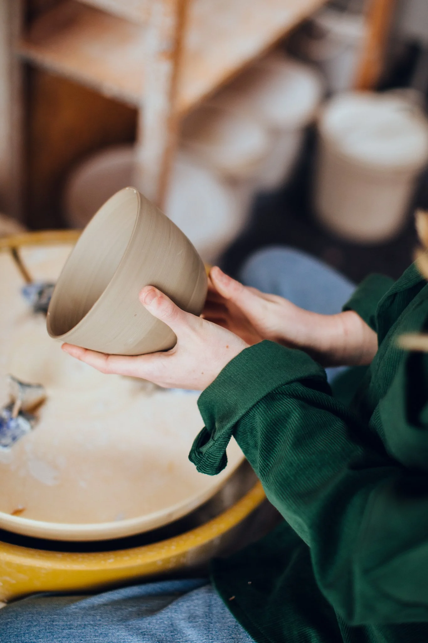 Person holding a ceramic bowl in a pottery studio.