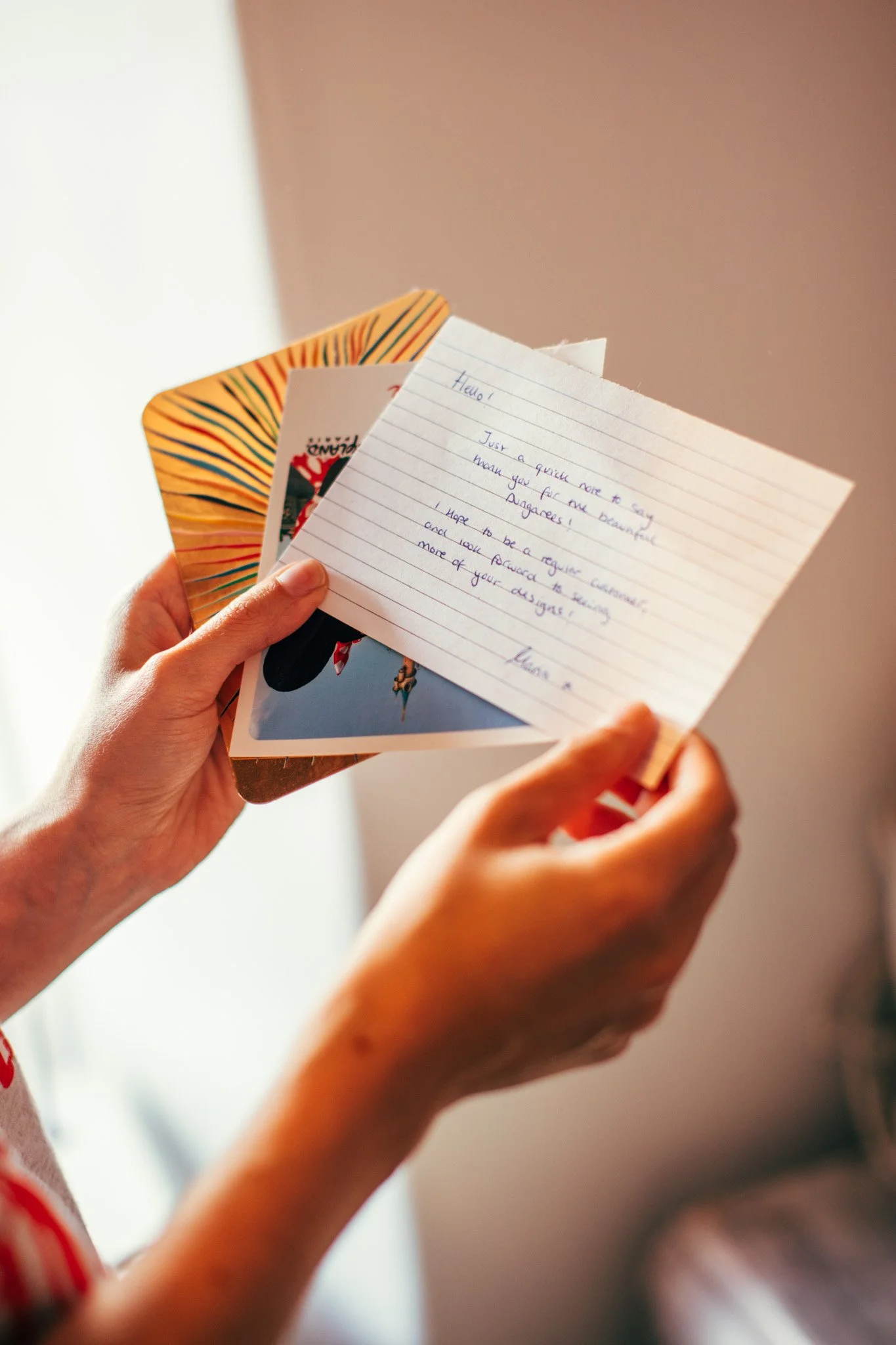 Person holding a handwritten note and several greeting cards.