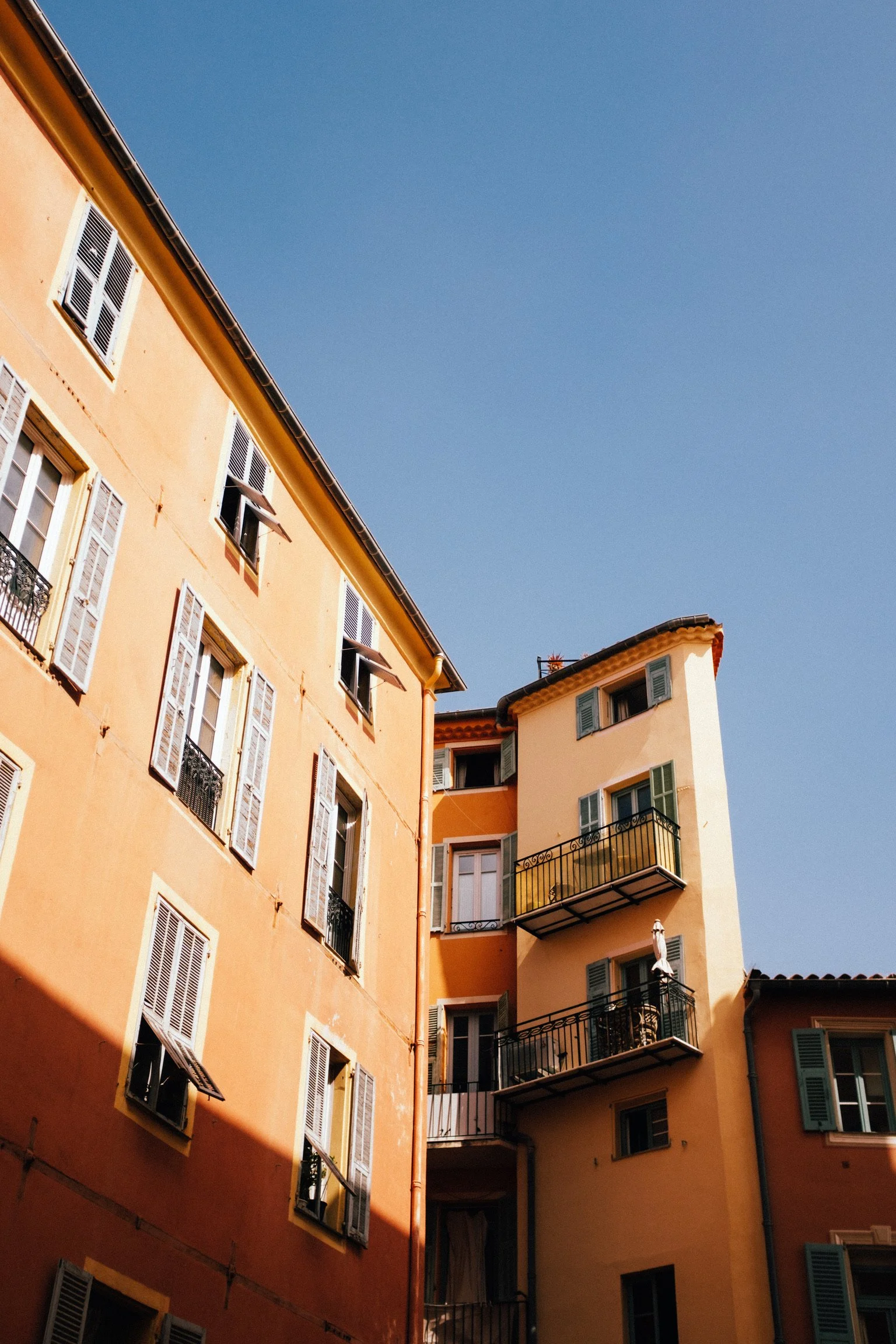 Colorful apartment building with open windows and balconies against a clear blue sky.