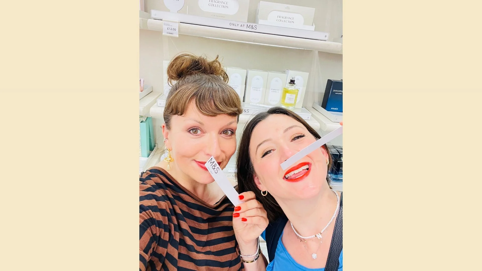 Nicola and Suzy, the hosts of On the Scent Podcast, are pictured smelling blotter strips in Marks & Spencer's fragrance department. They are smiling and excited to find such affordable perfumes!