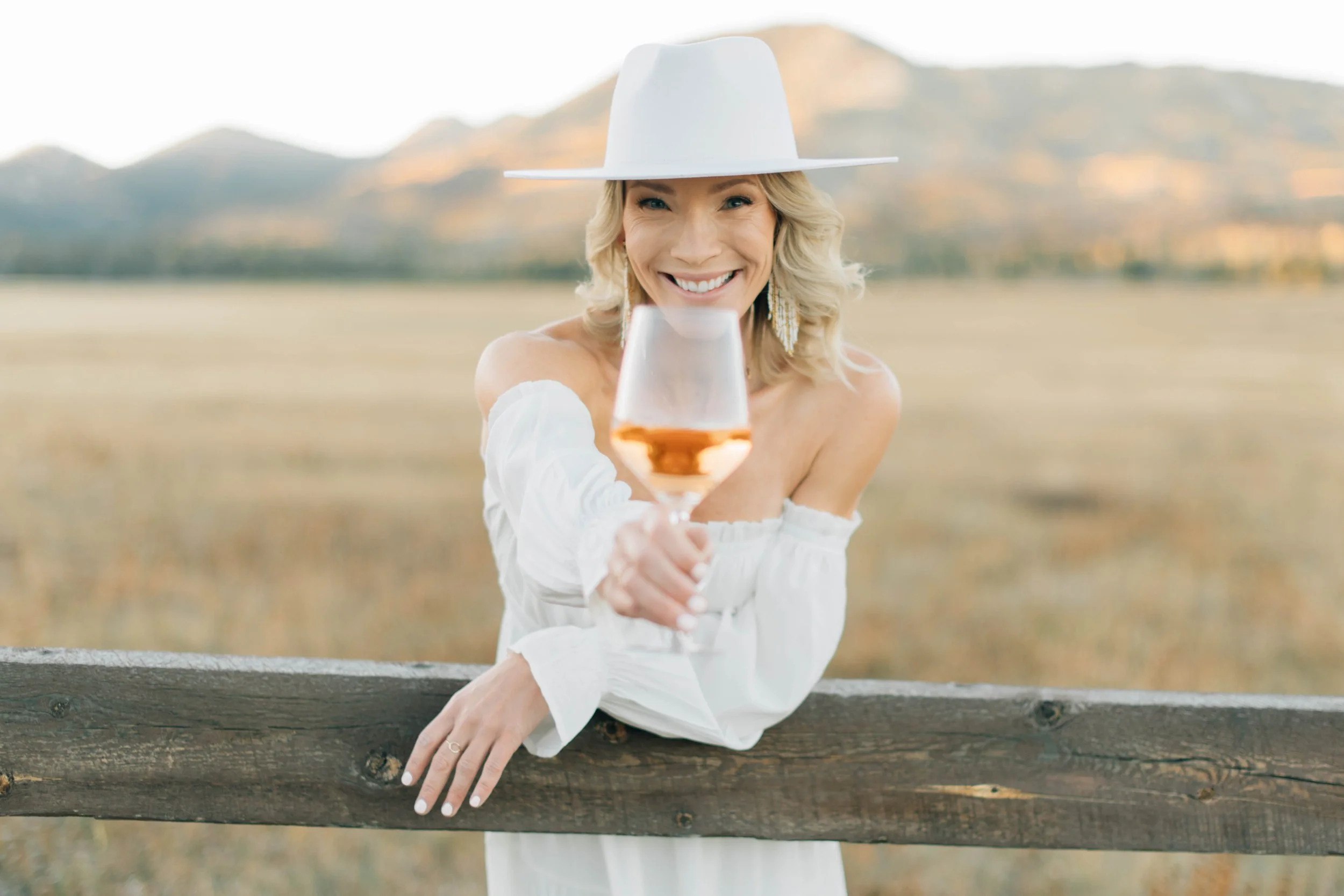 Wine tasting host holding a glass of rosé outdoors with mountain views